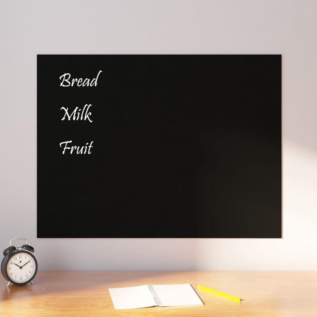 Eine schwarze Tafel mit Einkaufsliste: Brot, Milch, Obst. Eine Uhr und ein Notizblock sind in der Nähe.