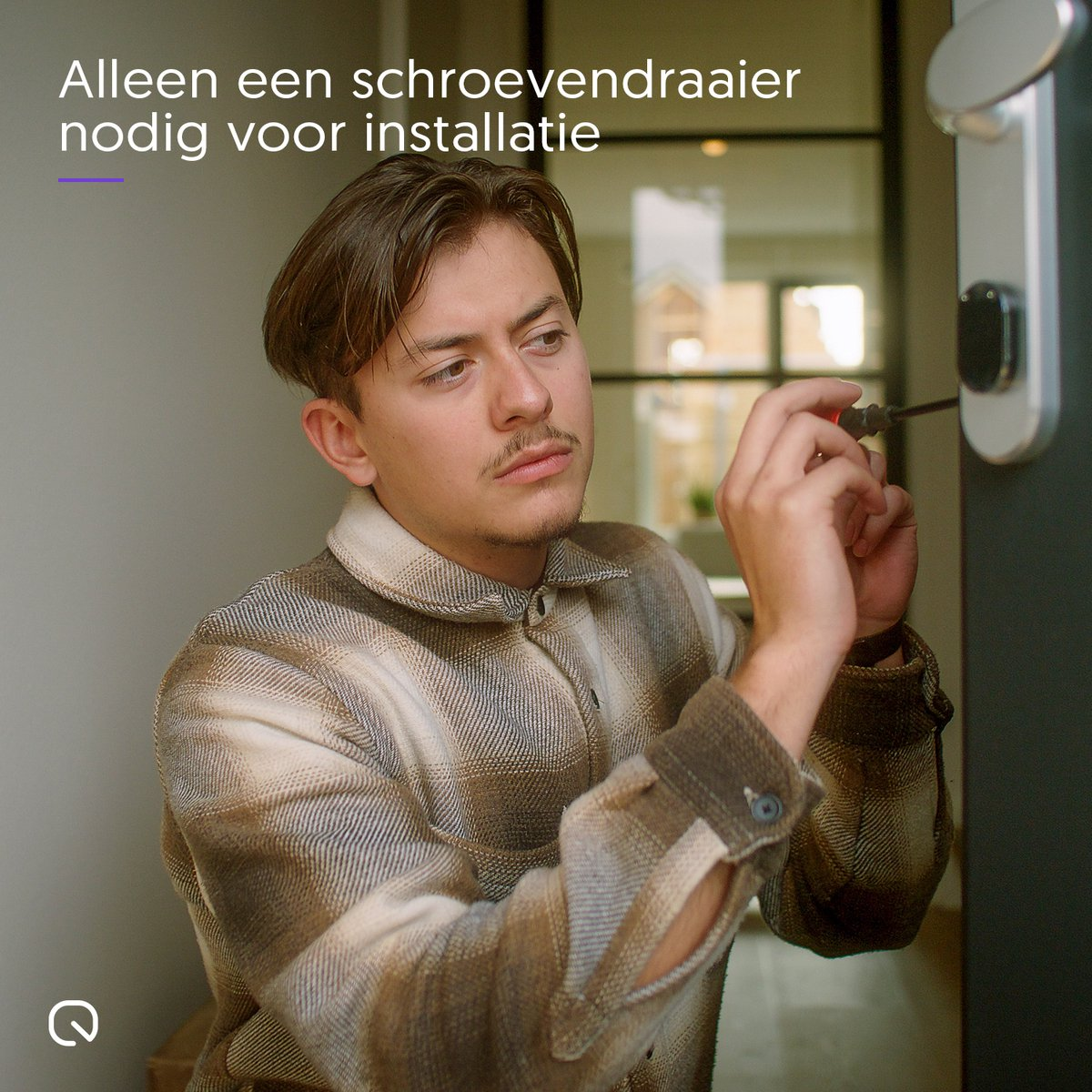 Man die een slim slot installeert met een schroevendraaier, in een goed verlichte kamer.