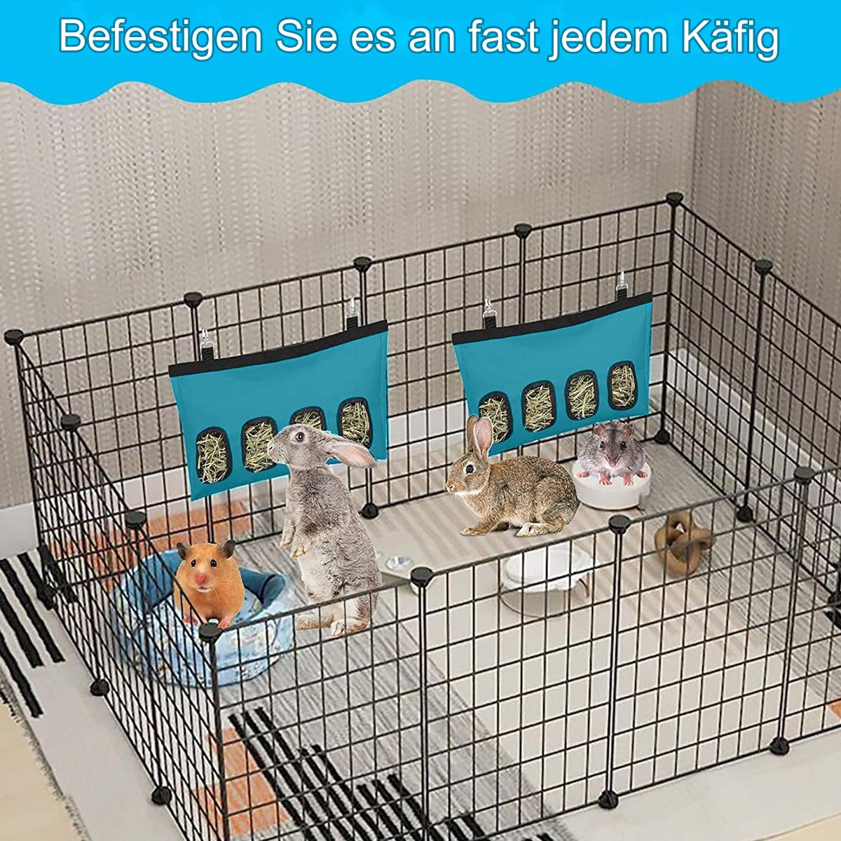 Ein Drahtgehege mit Kleintieren. Es gibt Kaninchen und einen Hamster. Zwei Heufutterautomaten sind vorhanden.