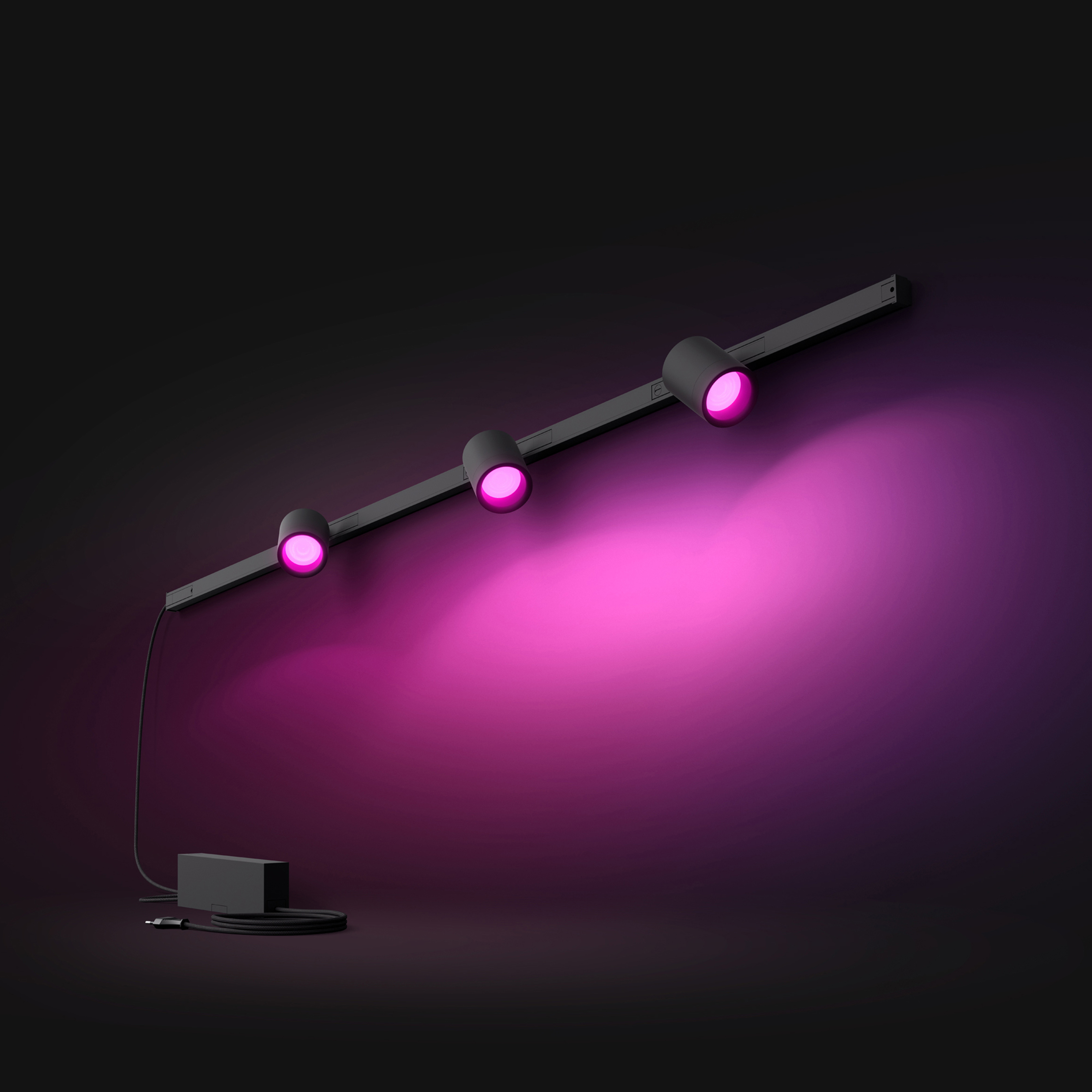 Drie zwarte spots op een rail. Roze licht schijnt van de lampen op een donkere achtergrond.