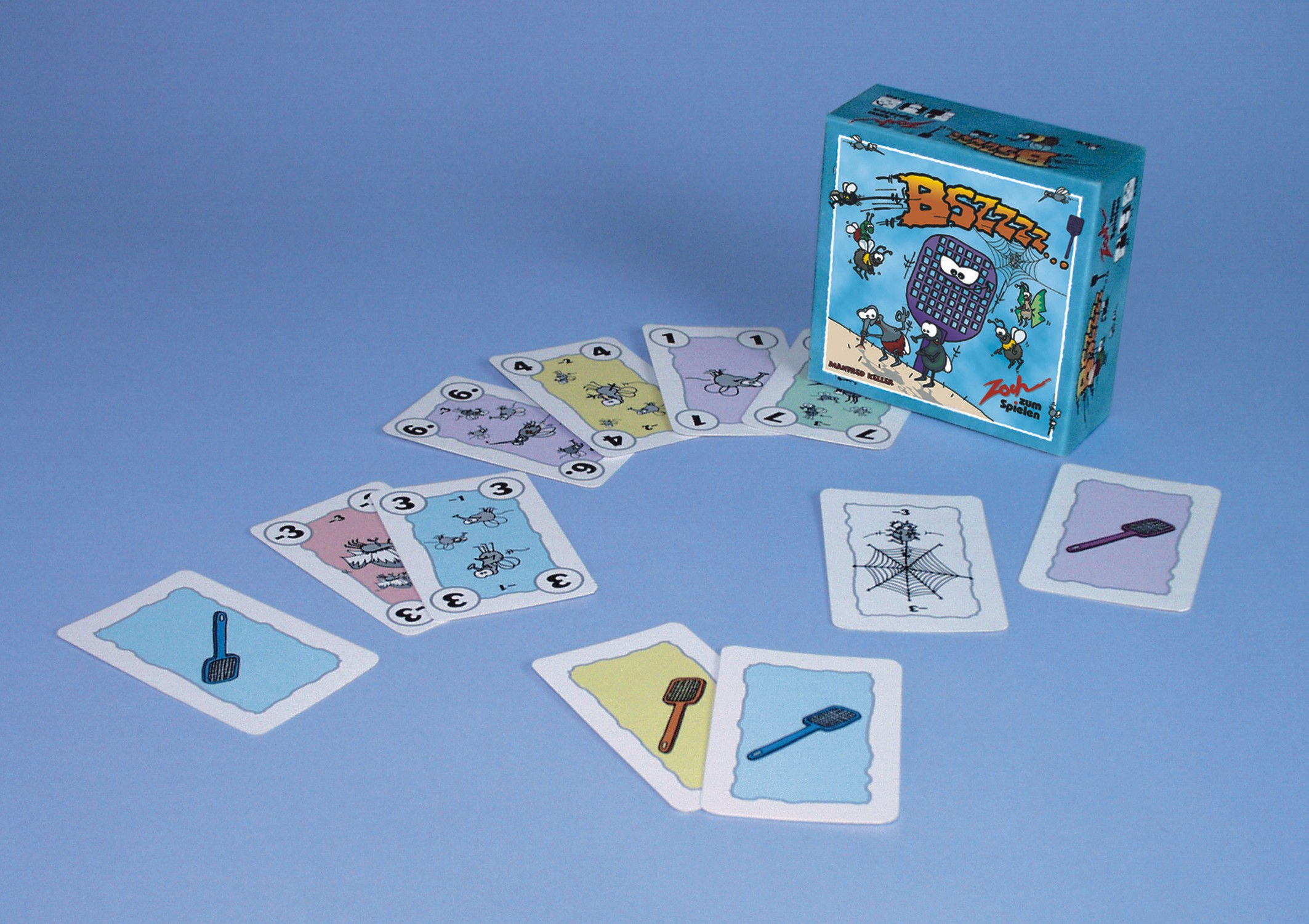 Ein Brettspiel mit Karten, die um eine Schachtel auf einer hellblauen Oberfläche verstreut sind.