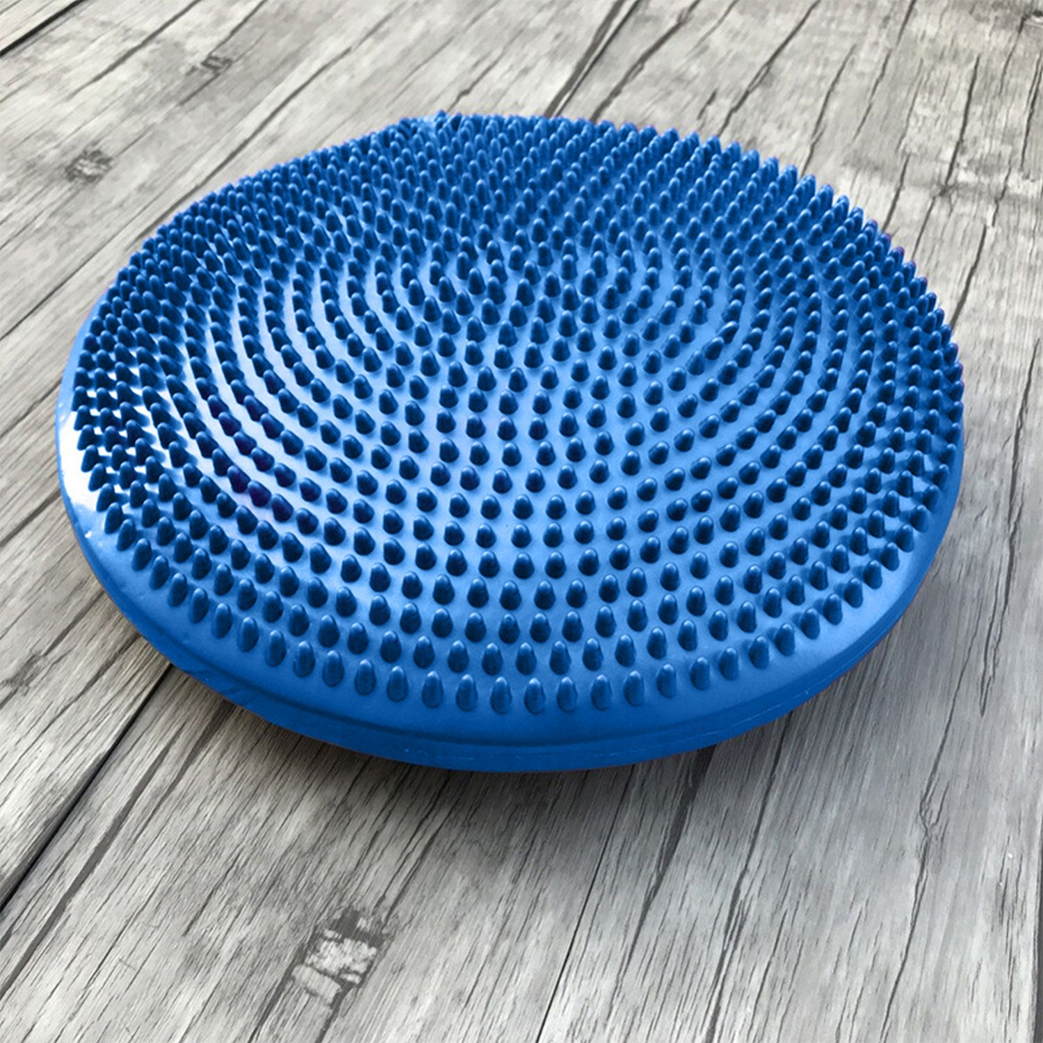 Un cuscino rotondo blu e appuntito su una superficie di legno.