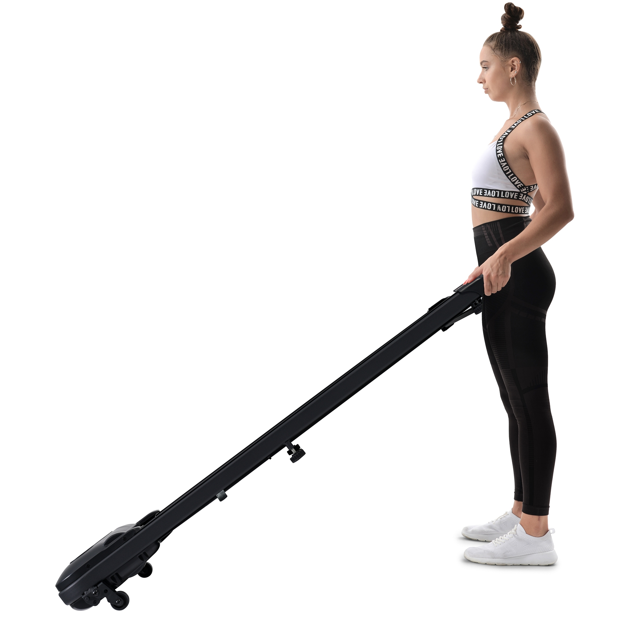 Frau hält ein schwarzes Laufband. Weißer Hintergrund, trägt ein weißes Oberteil und schwarze Leggings, Seitenansicht.