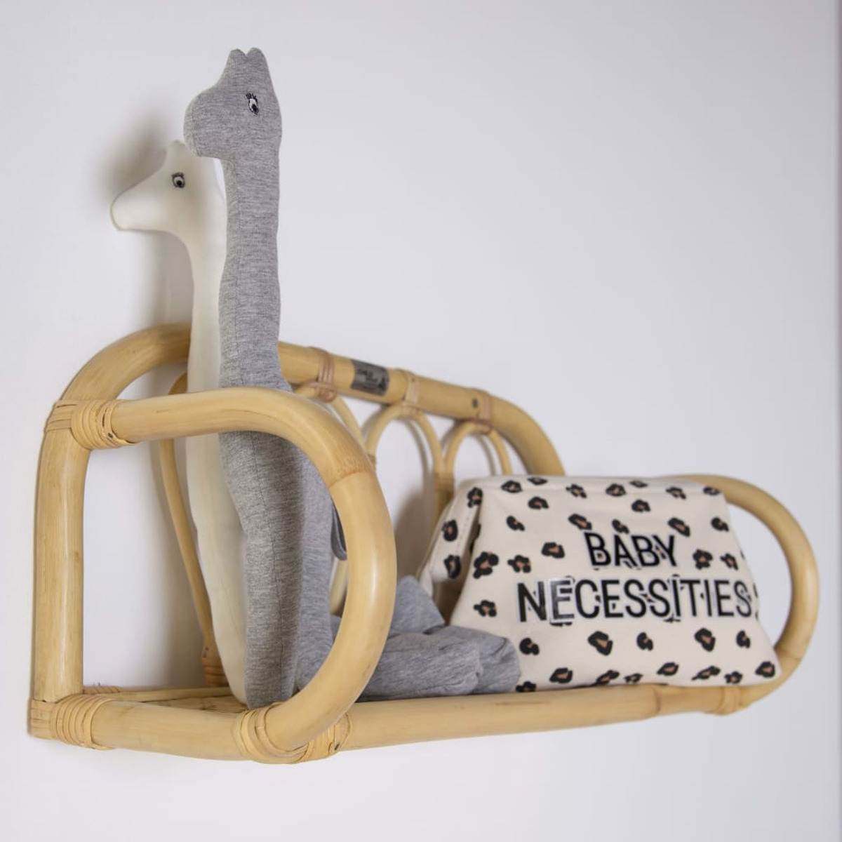 Ein Wandregal mit zwei Giraffenspielzeugen und einer Tasche mit der Aufschrift Baby Necessities.
