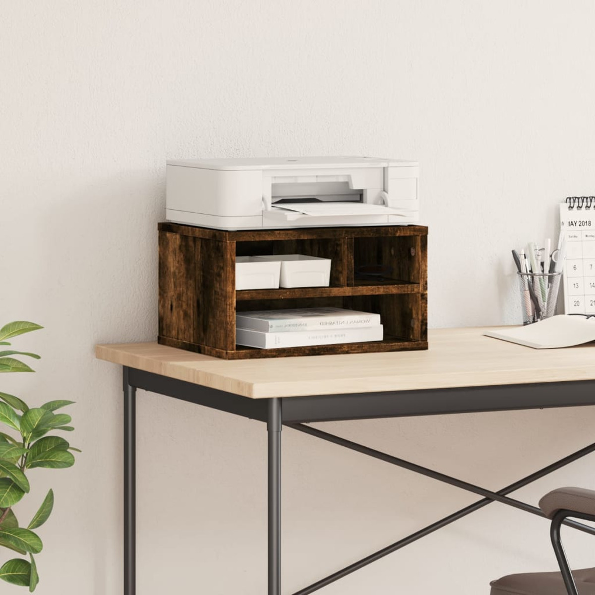 Ein Drucker auf einem Holzschreibtisch mit angebrachtem Regal. Der Schreibtisch befindet sich neben einer Wand und einem Kalender.