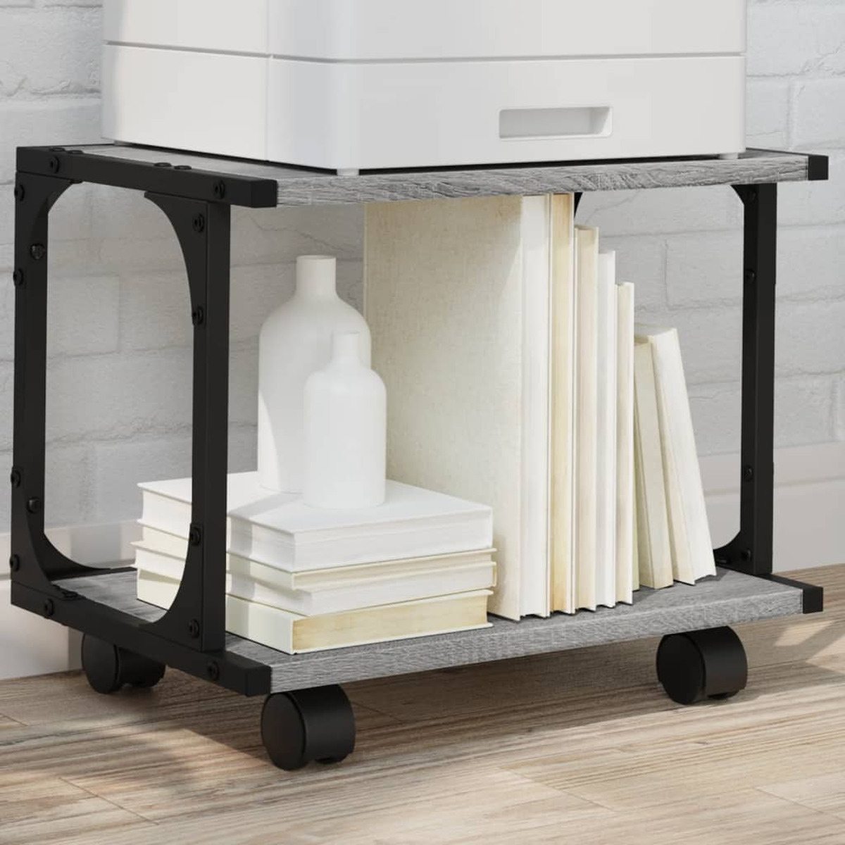 Mobiler Wagen mit Büchern, Vasen und einem weißen Drucker oben, mit schwarzen Metallrahmen.