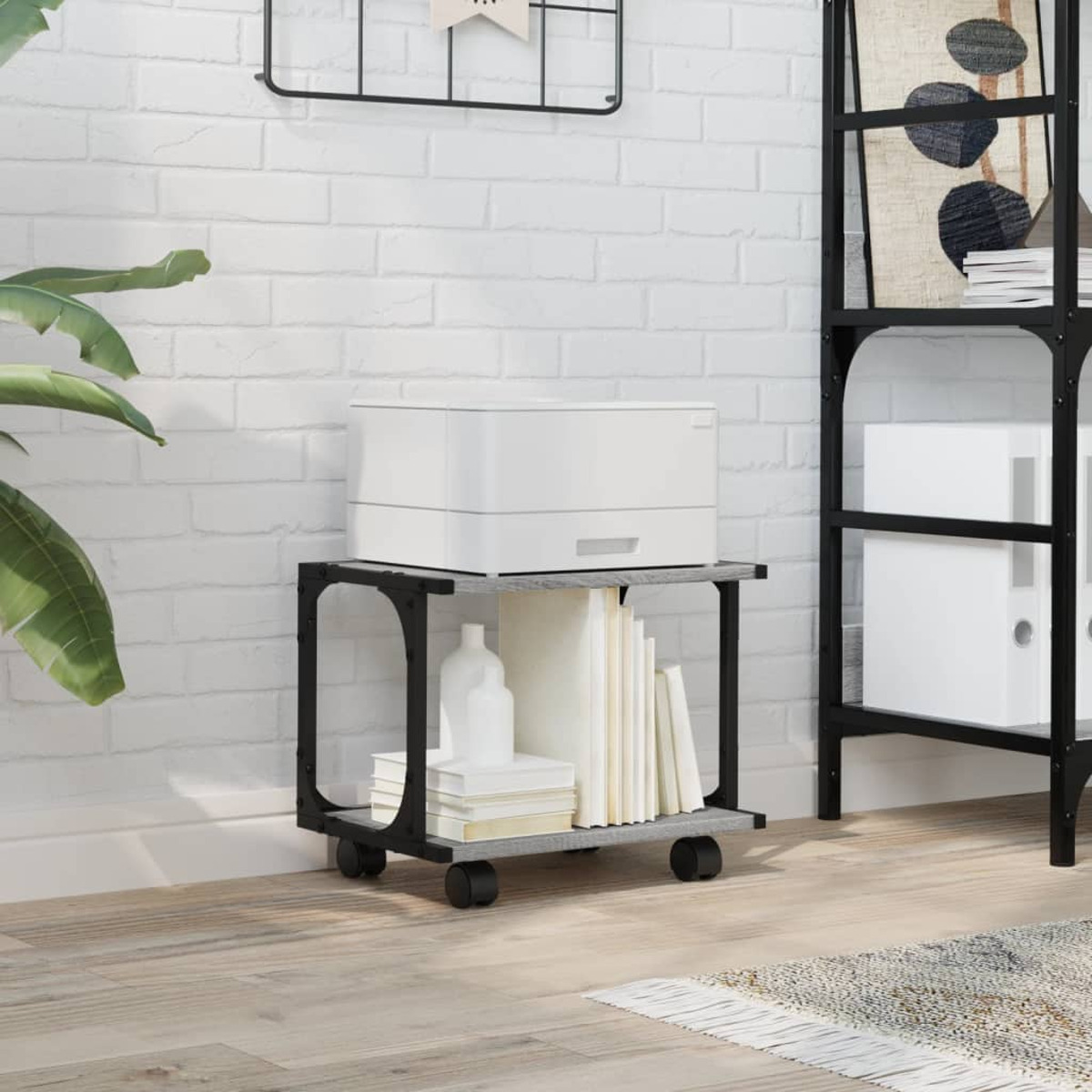 Druckerständer mit weißem Drucker, Büchern und einer Vase. Ziegelmauer, Holzboden und ein schwarzes Regal.