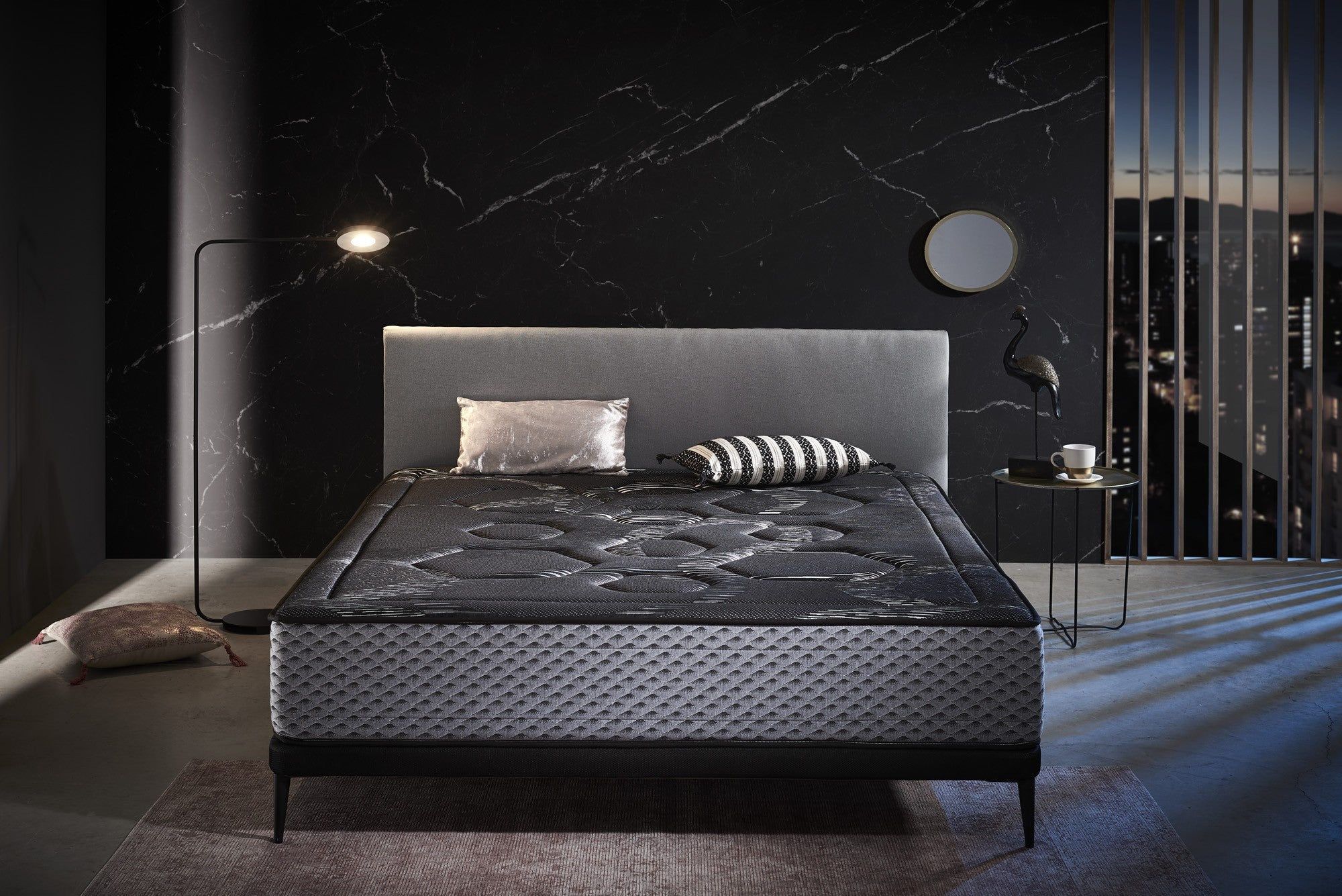 Un dormitorio con una cama, una lámpara de pie y una pared de mármol. Vista de la ciudad.