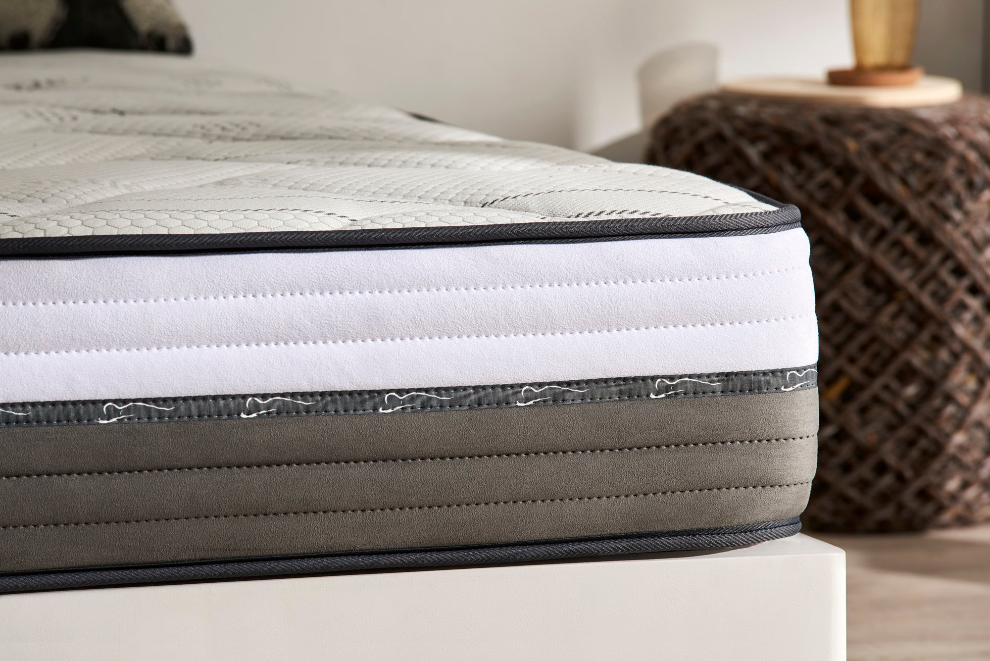 Primer plano de un colchón con capas blancas, grises y gris oscuro.