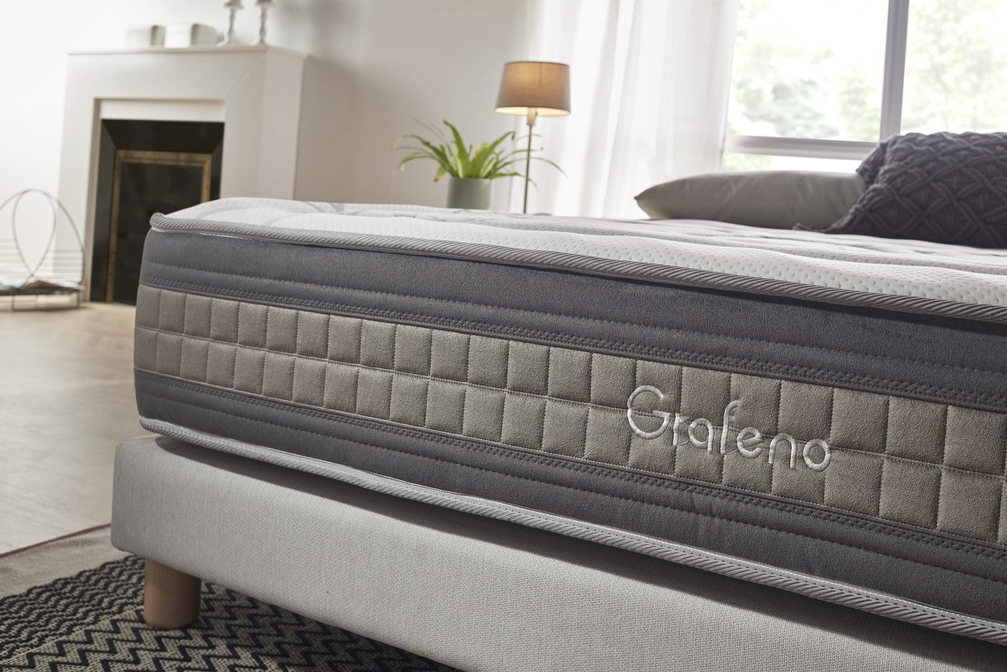Dormitorio con cama y pintura. El colchón tiene bordado la palabra 'Grafeno'.