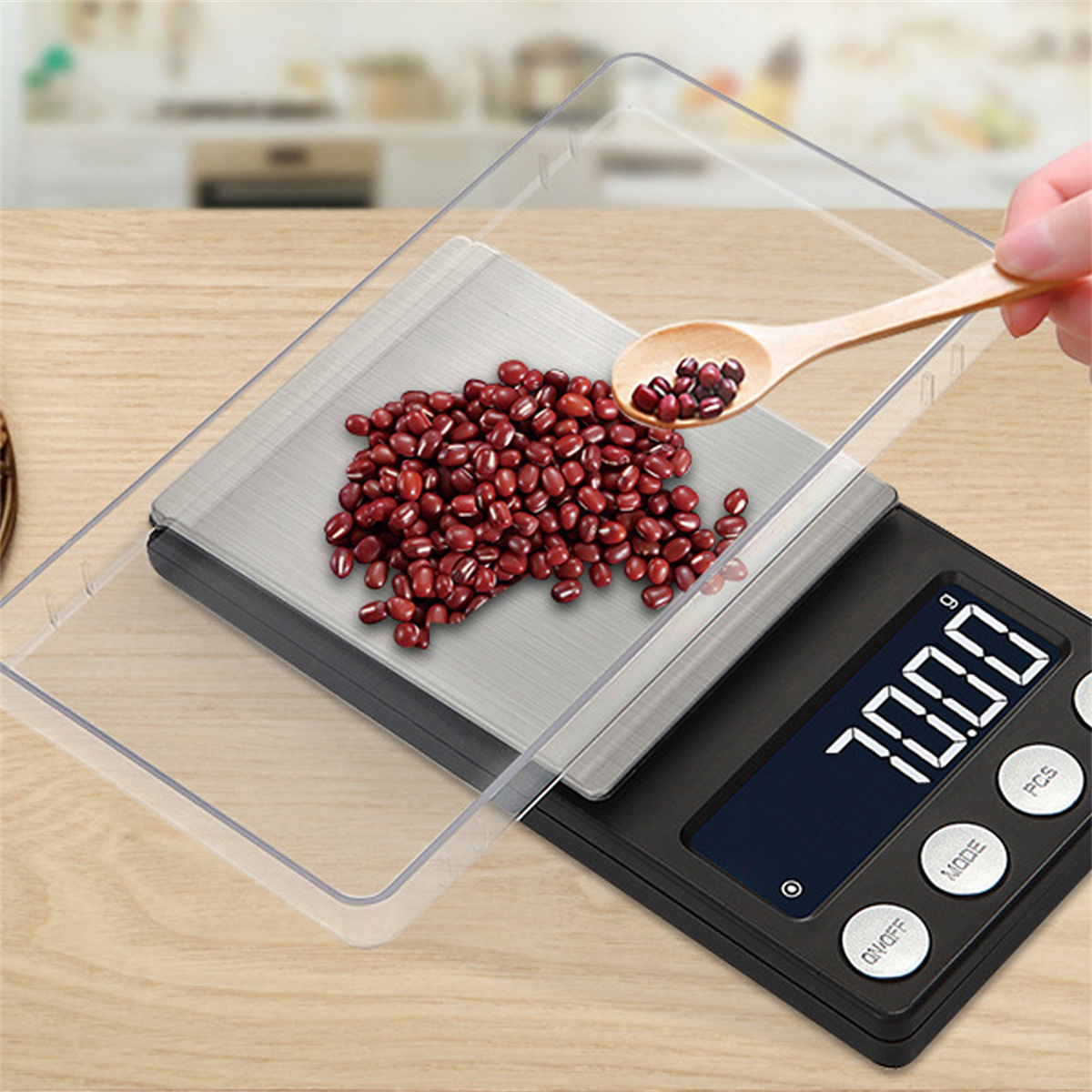Digitale Waage mit klarer Schale und Holzlöffel. Rote Bohnen liegen auf der Waage und im Löffel.