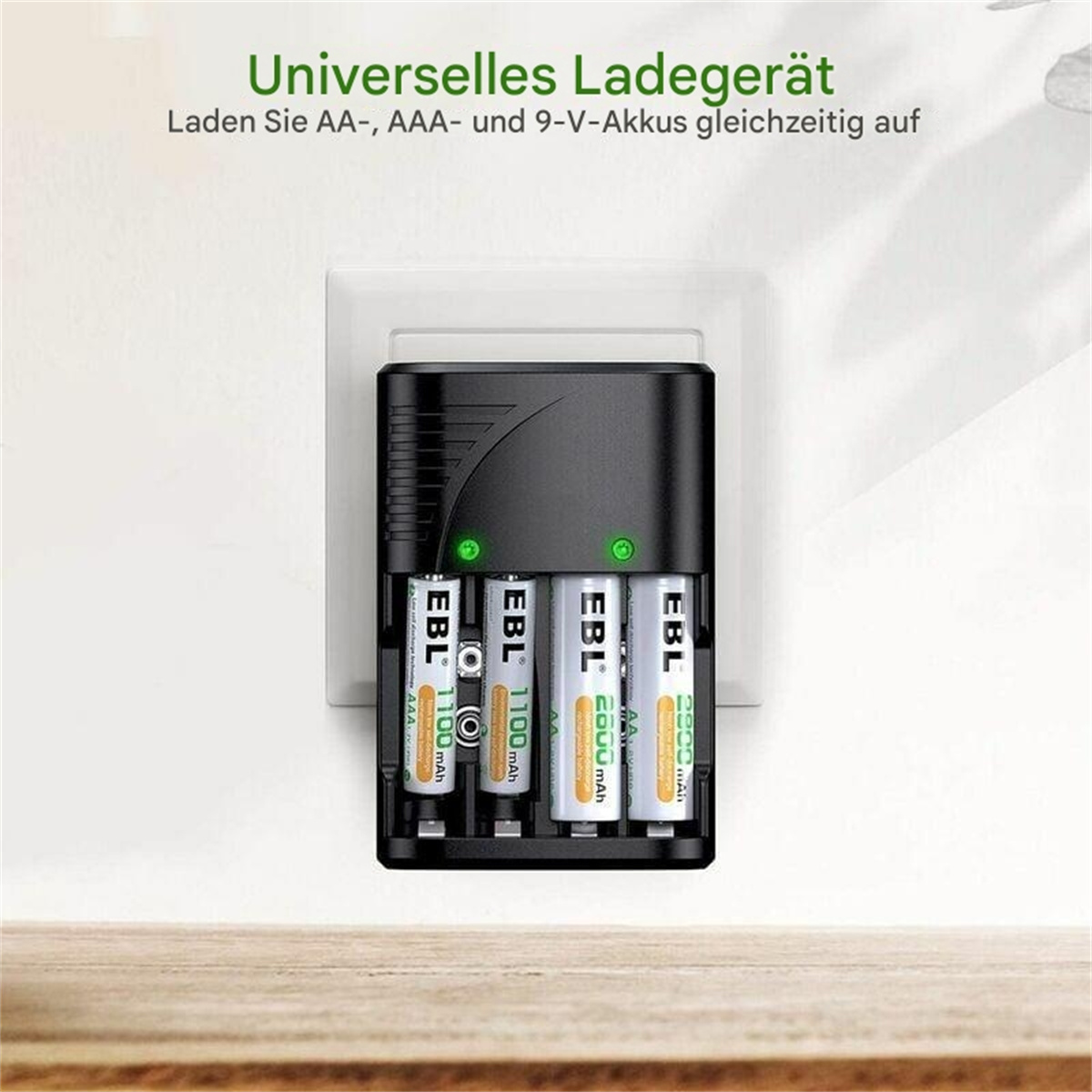 Ein schwarzes Batterieladegerät mit vier AA-Batterien im Inneren und einer Steckdose im Hintergrund.