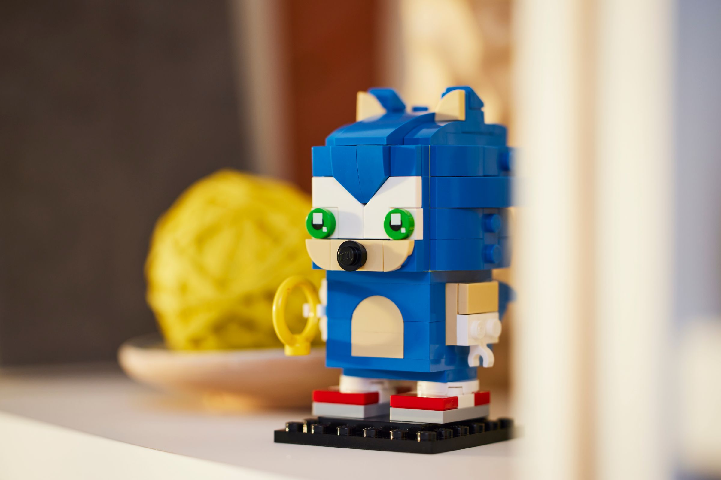 Sonic the Hedgehog Lego-Figur auf einem Regal. Gelbes Garn im Hintergrund.