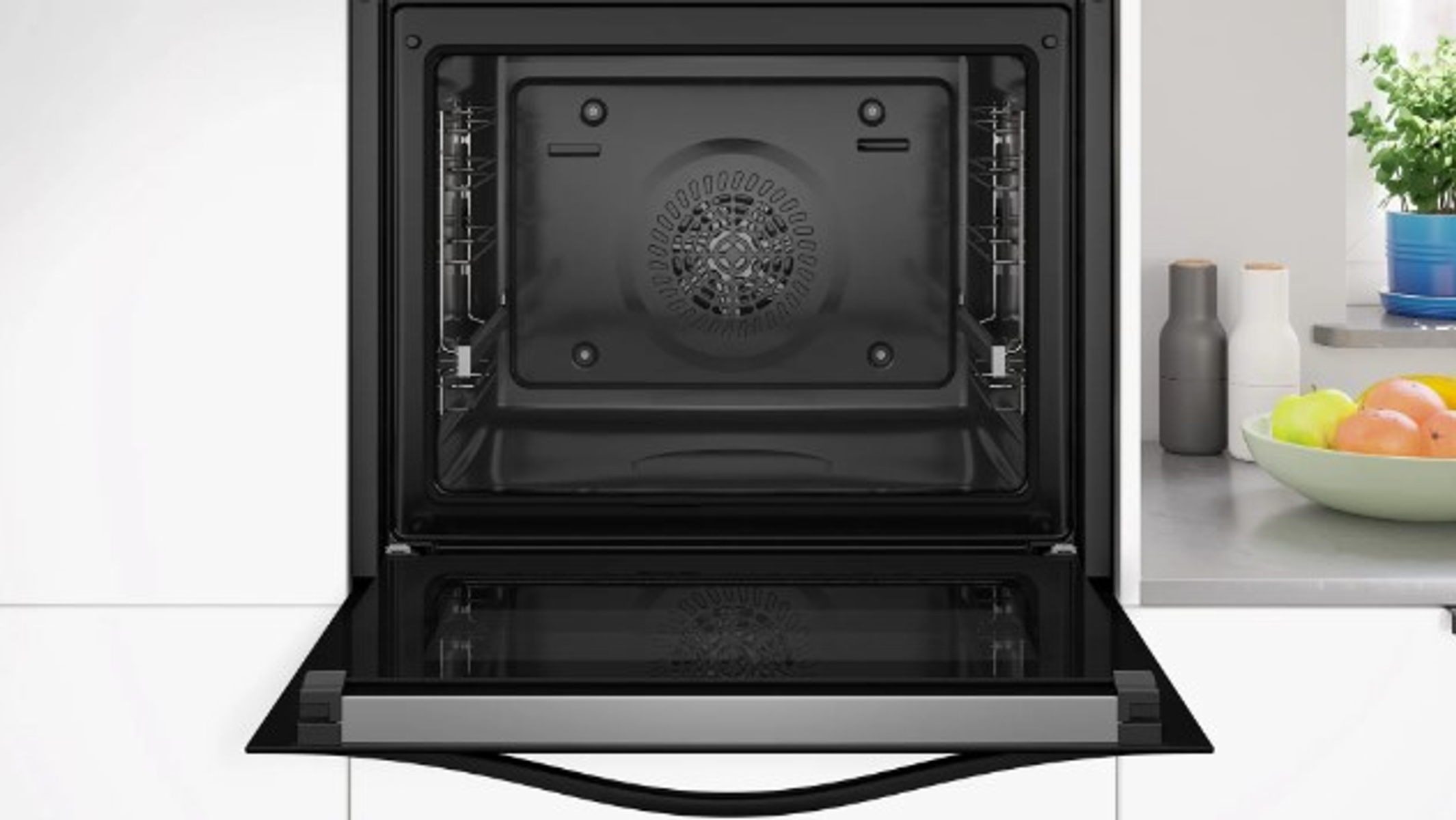 Interno del forno aperto con porta nera e vari oggetti da cucina visibili.