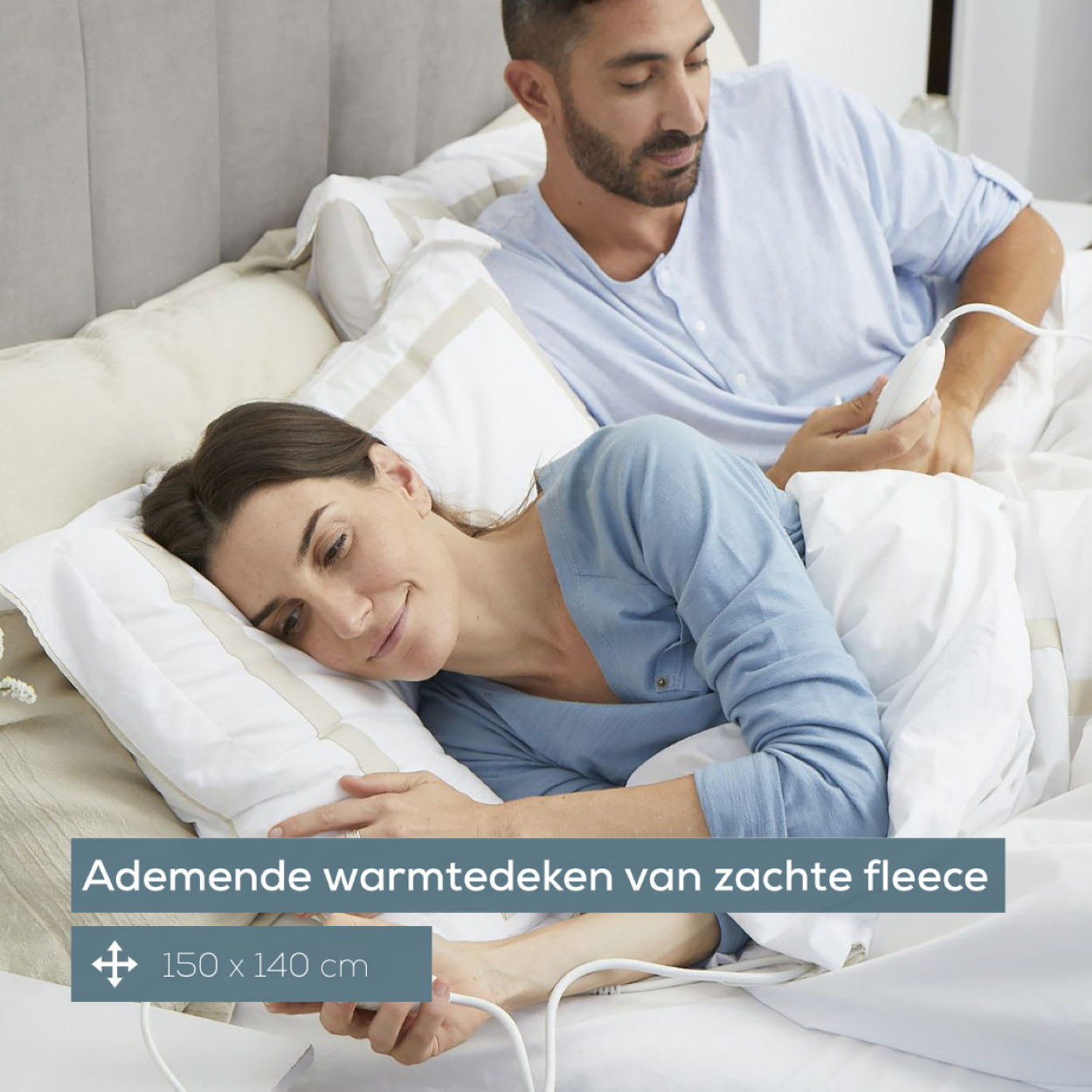 Pareja en la cama con manta eléctrica. La mujer está acostada, sonriendo y feliz.