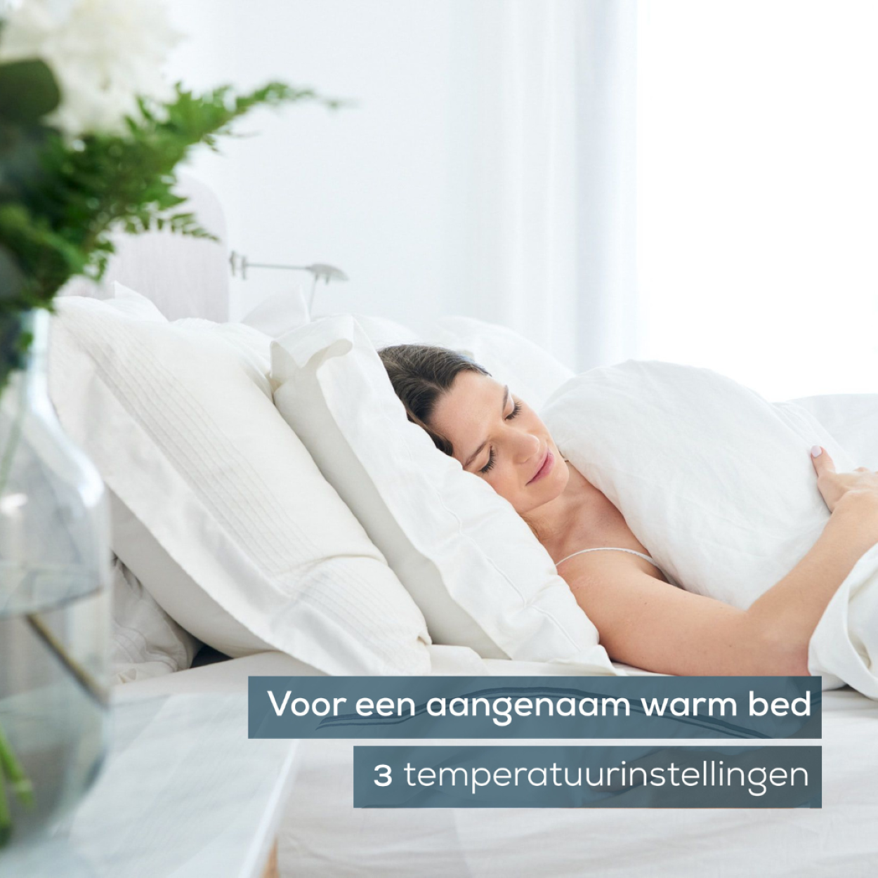 Mujer en cama, cubierta con edredón. Texto: 'Voor een aangenaam warm bed'.