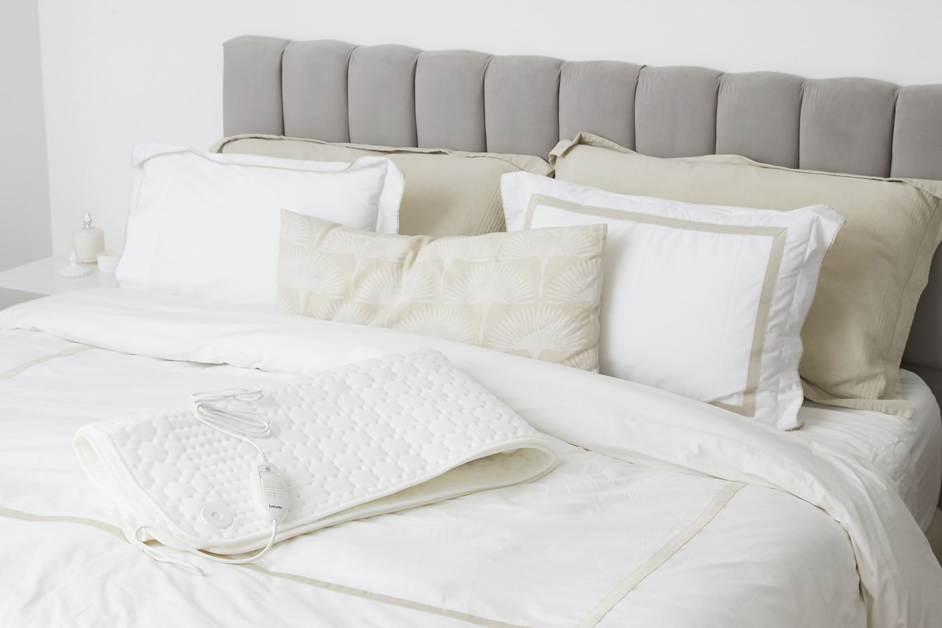 Dormitorio con ropa de cama blanca y una manta eléctrica blanca.
