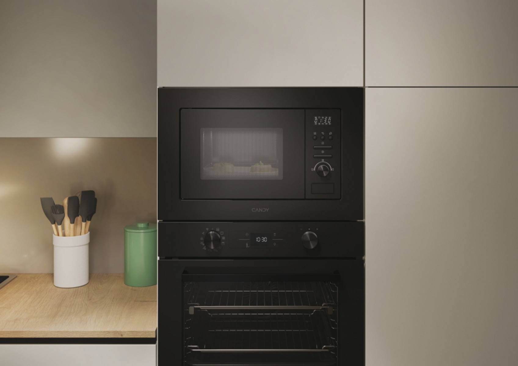 Czarna kuchenka mikrofalowa i piekarnik, wbudowane w ścianę kuchni. Drewniany blat i zielony pojemnik po lewej.