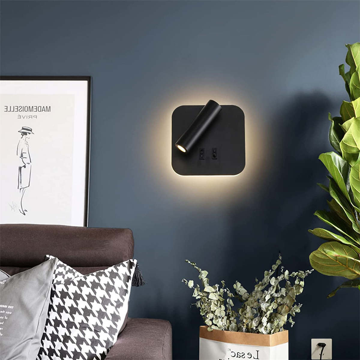 Wandlampe an dunkler Wand mit Pflanze und Bild.