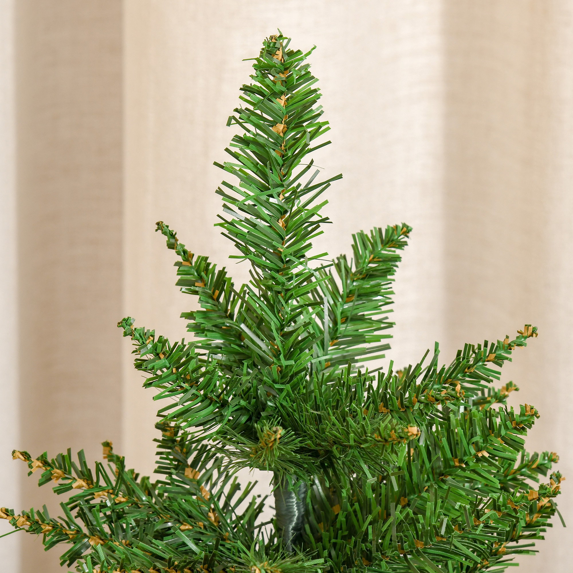 Primer plano de la parte superior de un árbol de Navidad verde artificial, ramas con agujas.