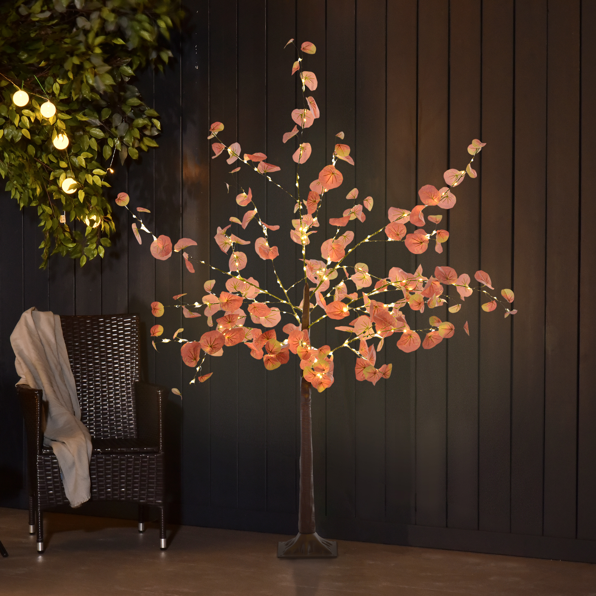 Una escena al aire libre con un árbol iluminado, una silla y una pared.
