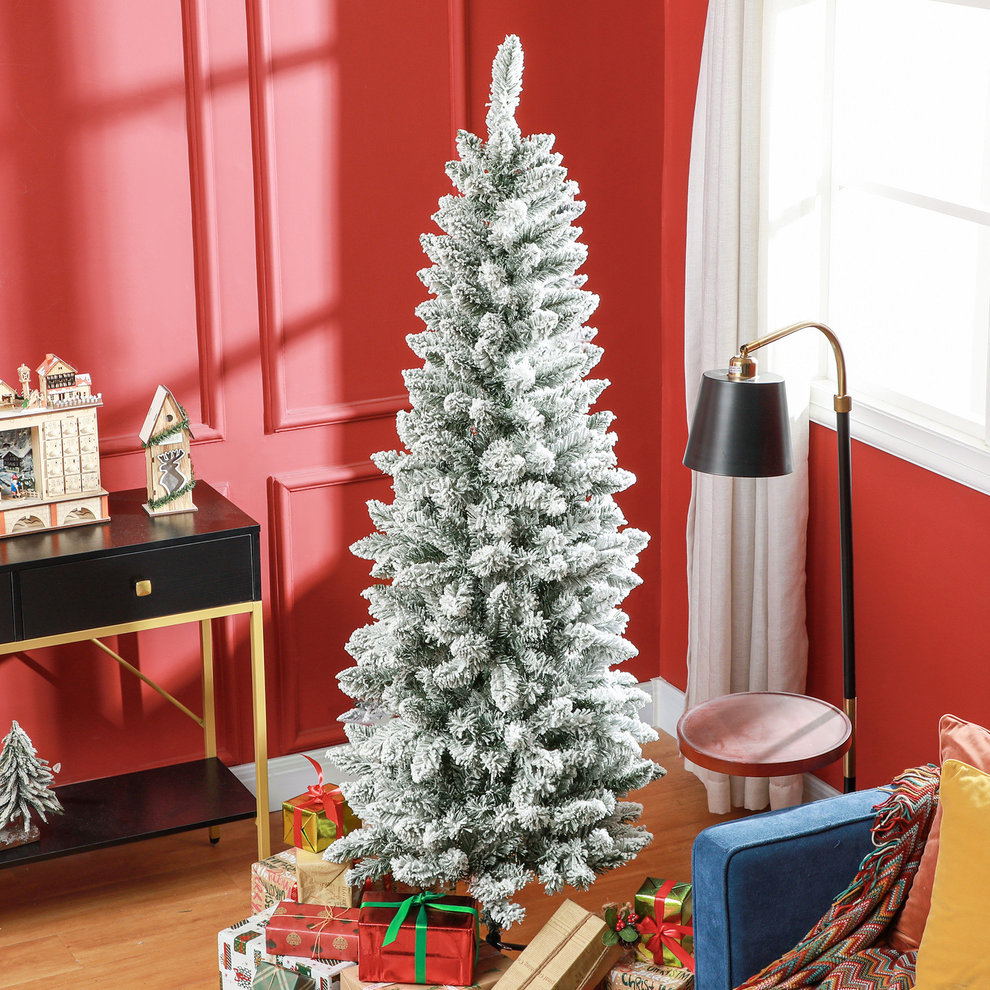 Árbol de Navidad alto cubierto de nieve en una habitación, con regalos debajo.