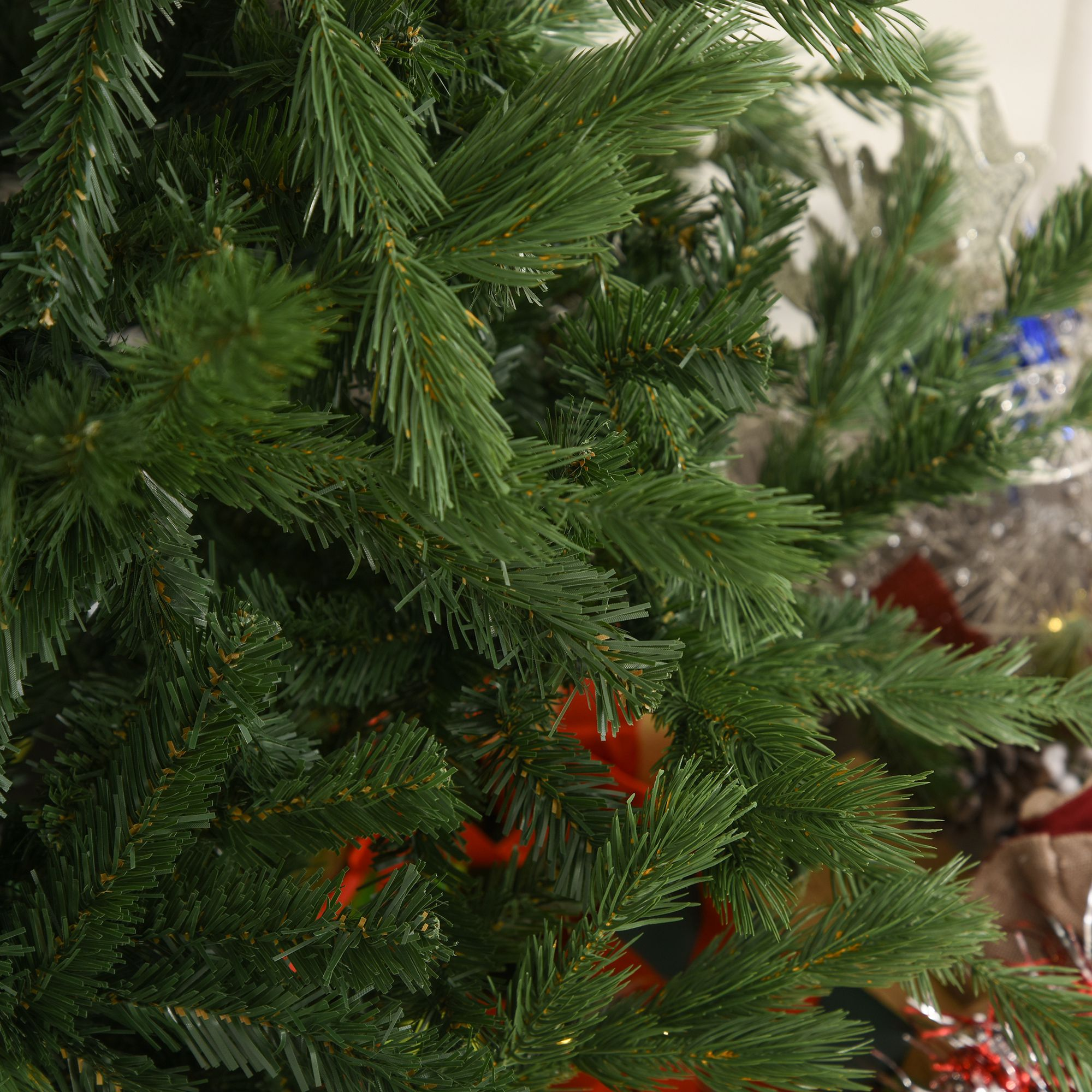 Primer plano de un árbol de Navidad artificial verde con agujas y ramas, algunas borrosas en el fondo.