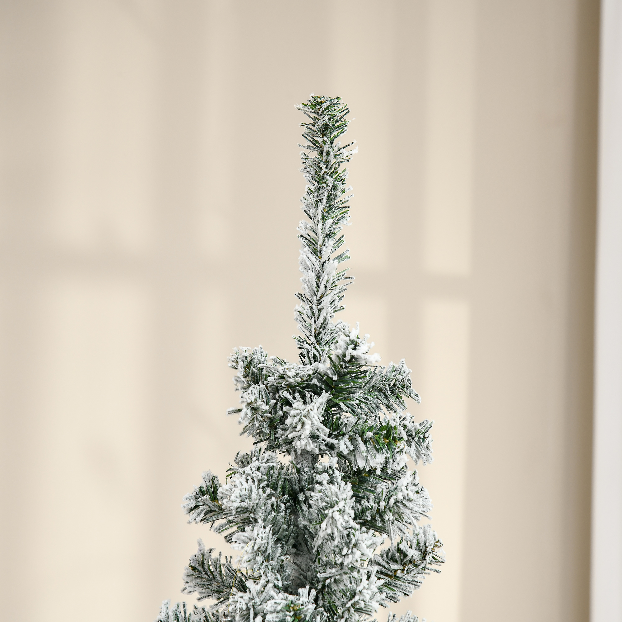 Primer plano de la parte superior de un árbol de Navidad cubierto de nieve contra un fondo borroso.