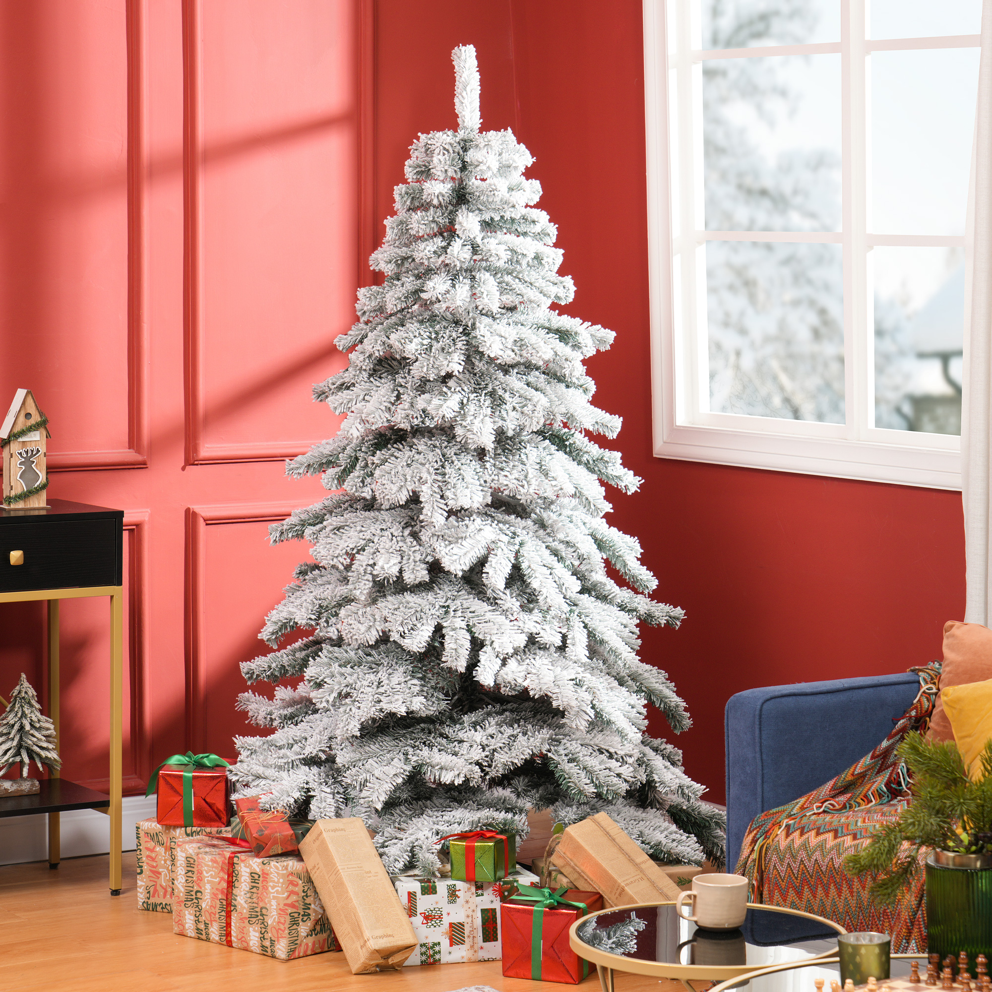 Árbol de Navidad cubierto de nieve con regalos. Fondo de pared roja, con ventana y mesa auxiliar. Escena acogedora.