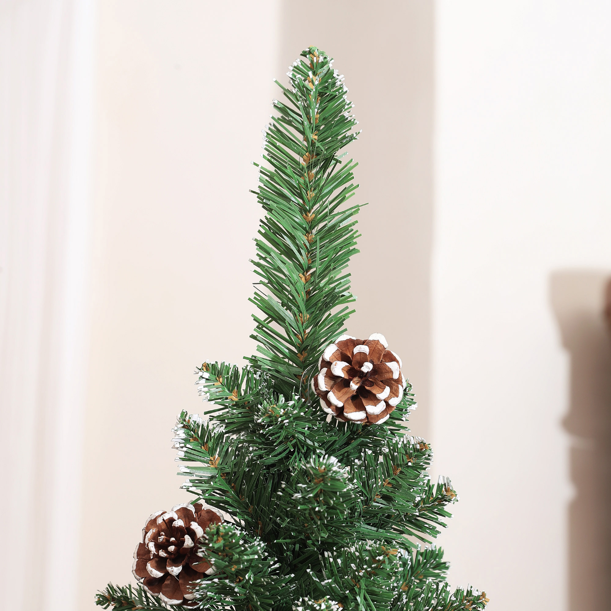 Primer plano de la parte superior de un árbol de Navidad con dos piñas y una capa de escarcha blanca.