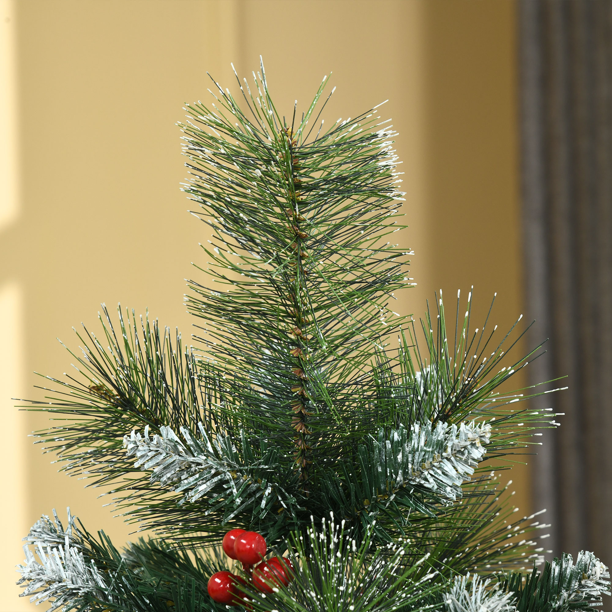 Primer plano de una rama de árbol de Navidad con bayas rojas y efecto de nieve.
