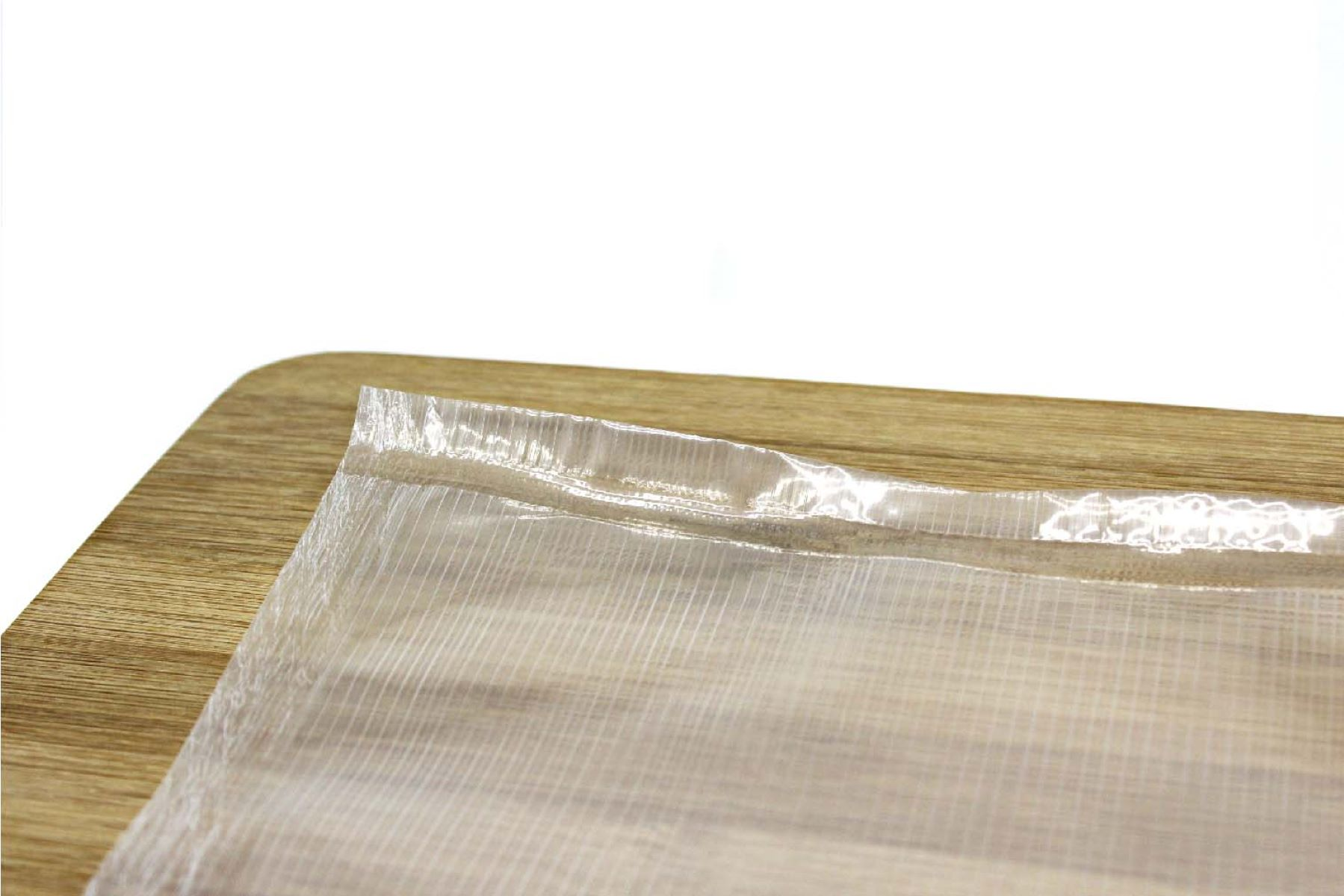 Una bolsa de plástico transparente sobre una superficie de madera. La bolsa está en primer plano y muestra la textura.