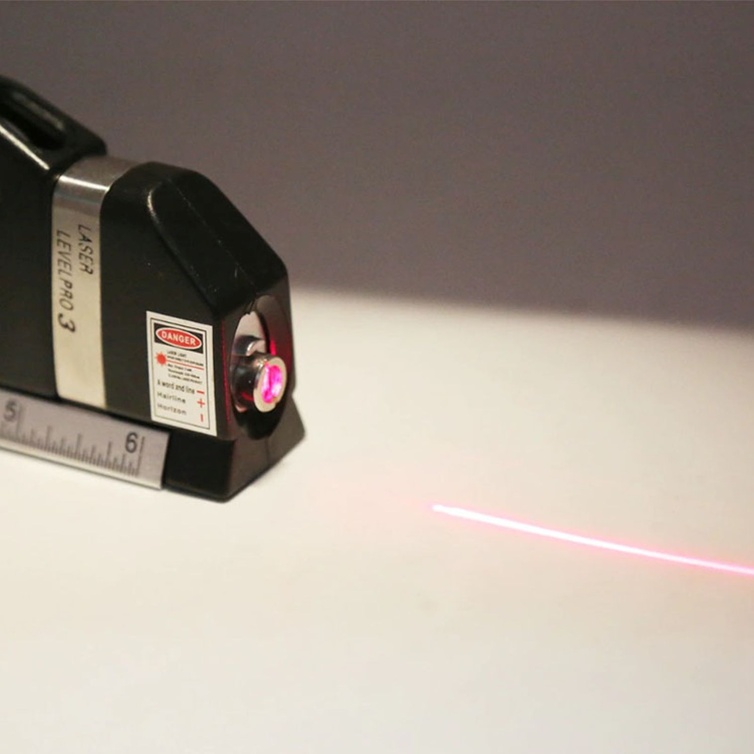 Ein Laser-Nivelliergerät, das einen roten Laserstrahl auf einer weißen Oberfläche aussendet.