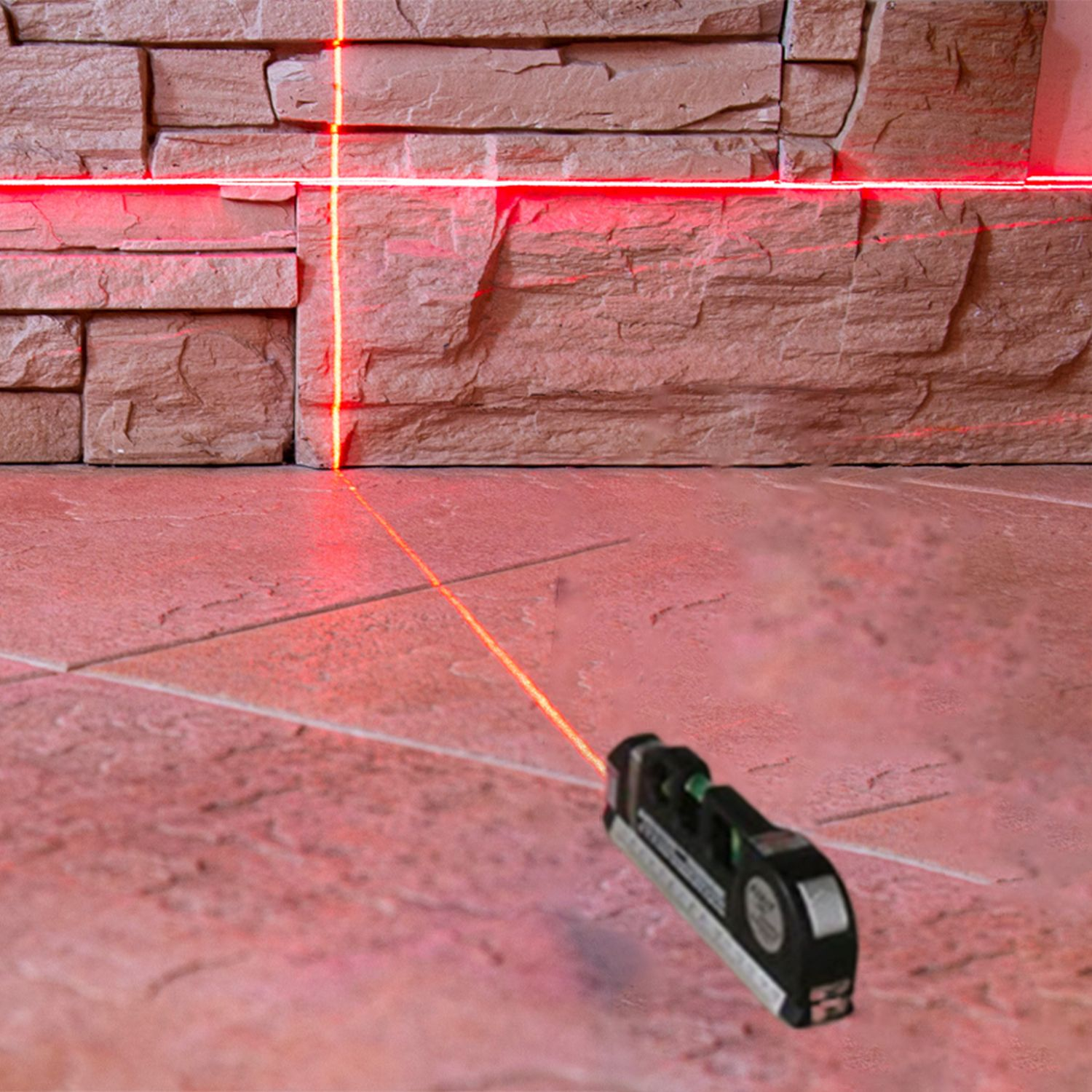Ein roter Laser-Wasserwaage, die eine Linie auf eine Backsteinmauer und einen Boden projiziert.