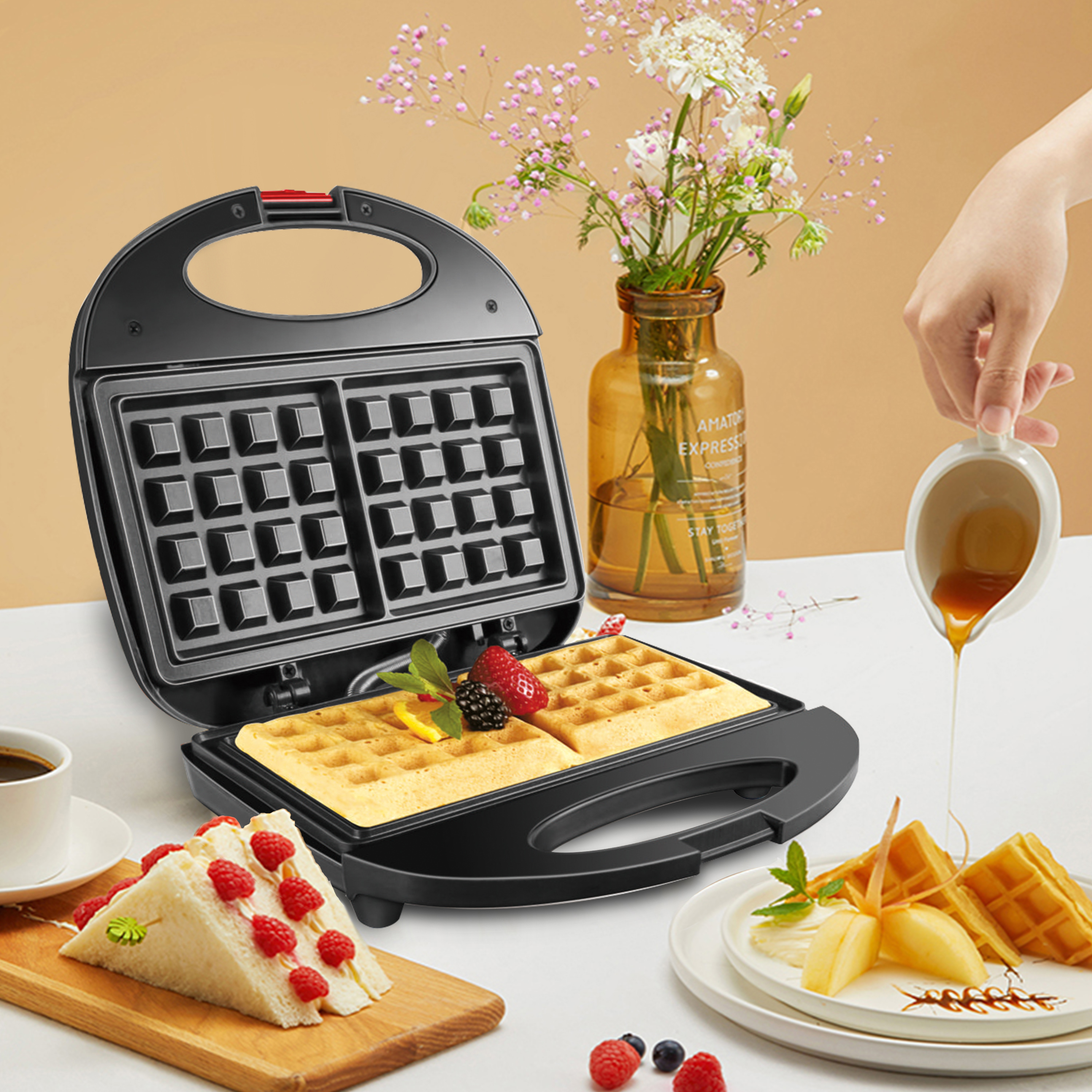 Una macchina per waffle con waffle all'interno, un piatto di waffle e un panino. Si versa lo sciroppo.