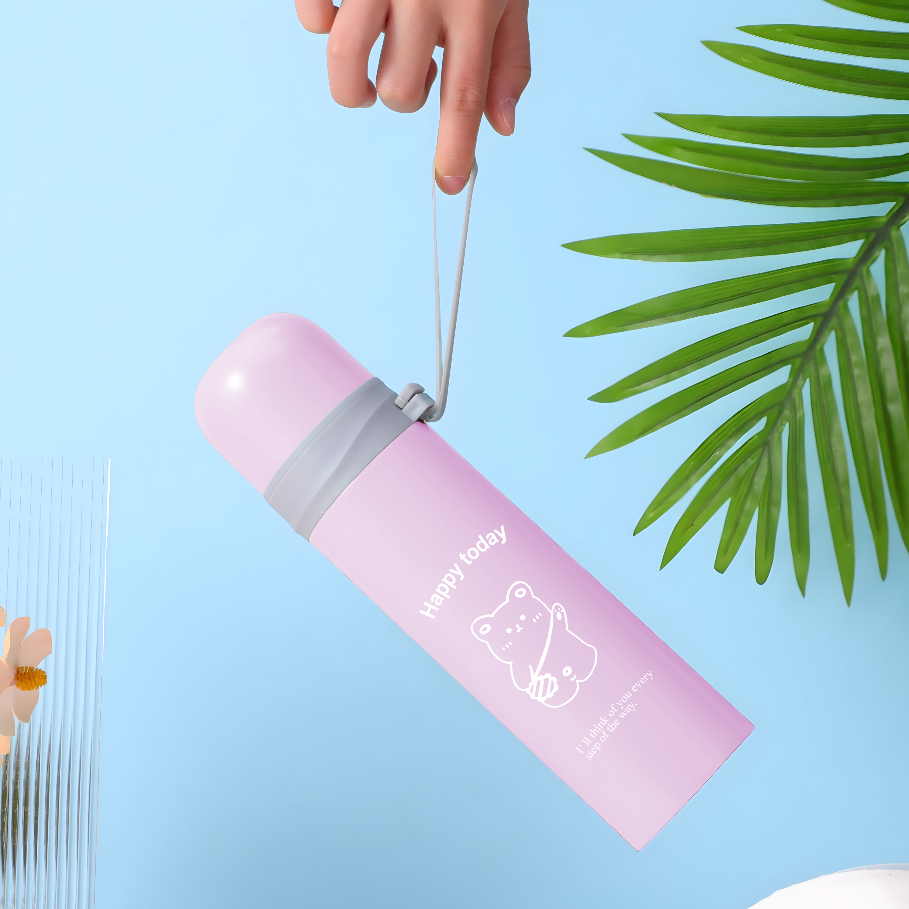 Eine pinkfarbene Wasserflasche mit Bärenillustration wird von einer Hand vor blauem Hintergrund gehalten.