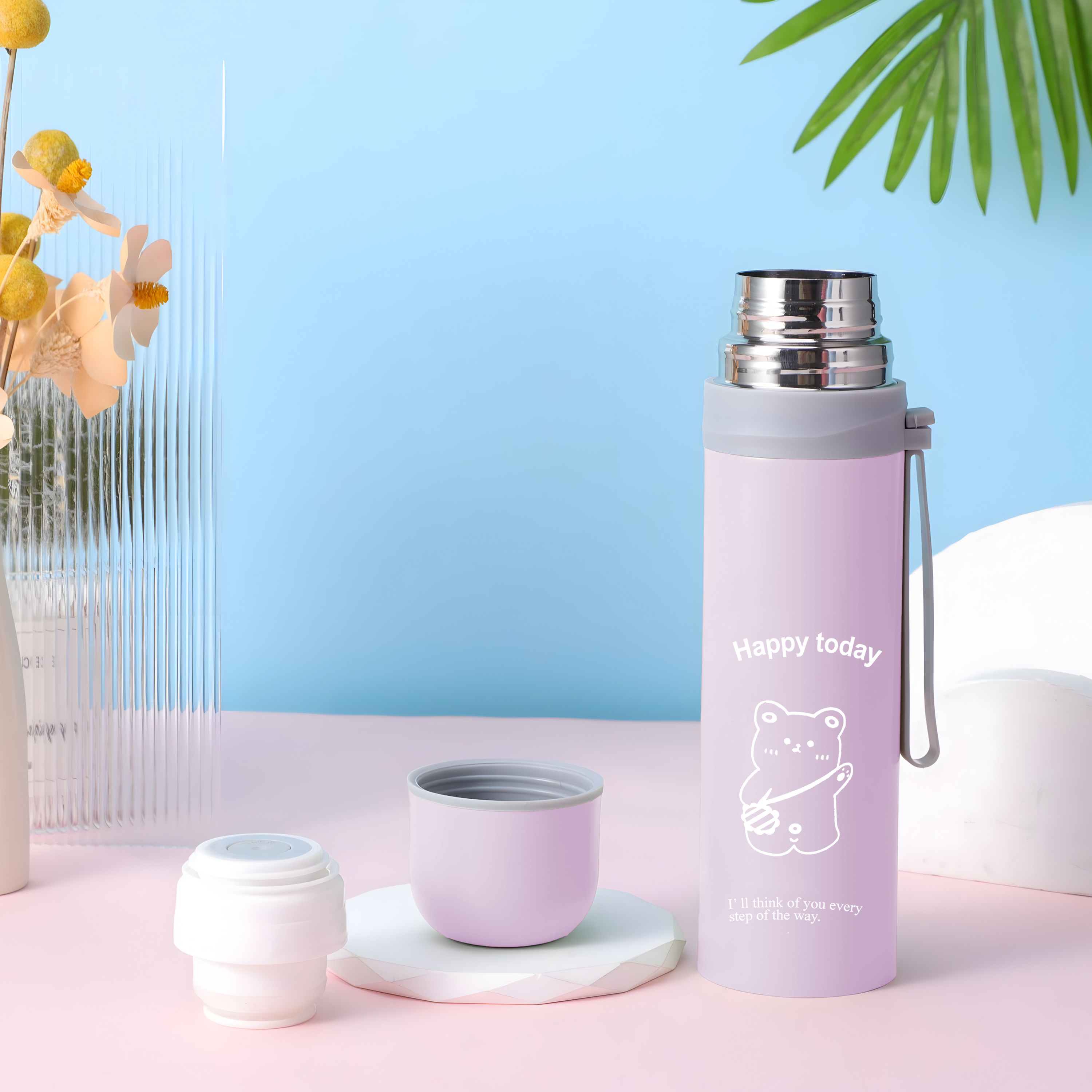 Eine lila Wasserflasche mit einer weißen Bärengrafik. Die Flasche steht neben Deckel und Verschluss.
