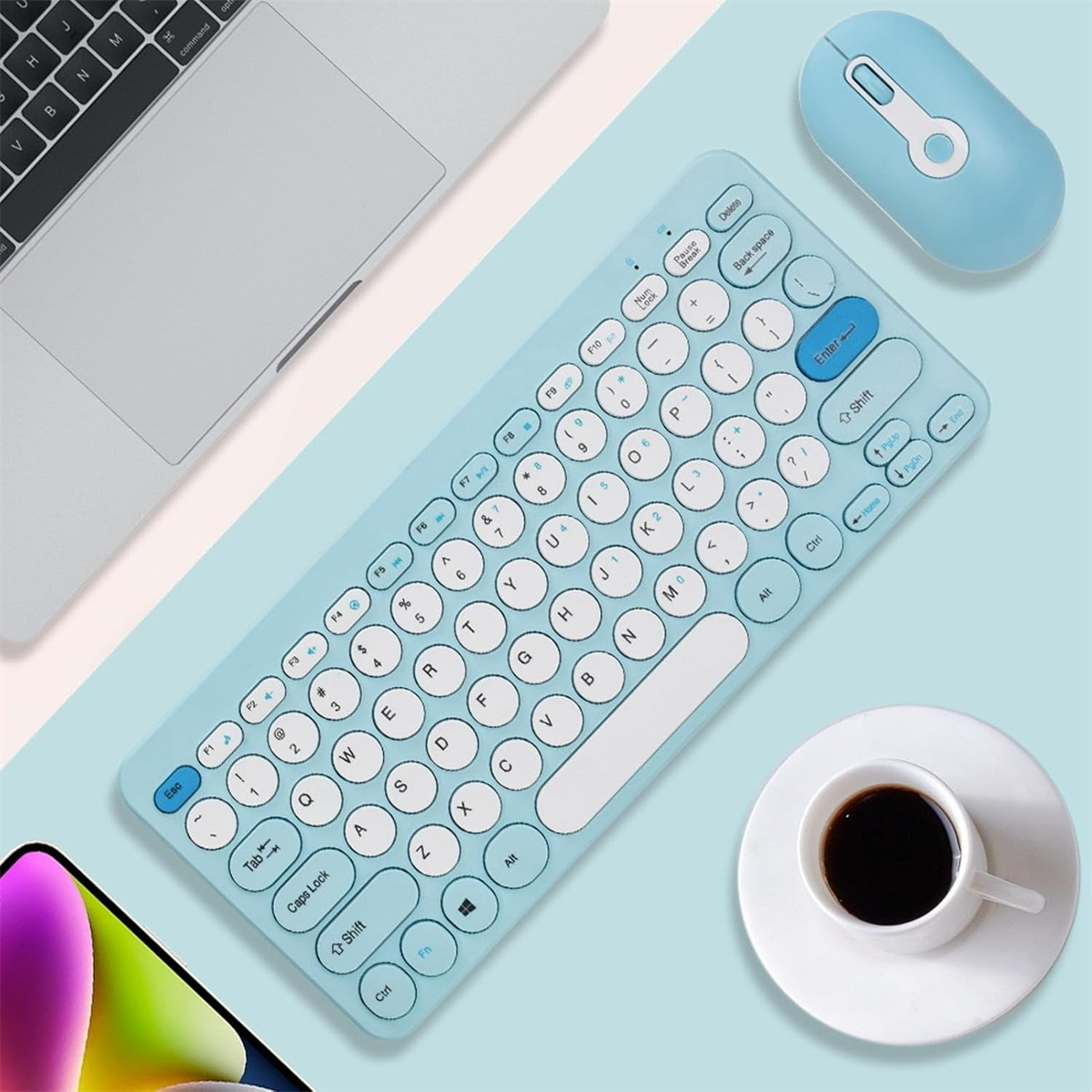 Blaue Tastatur und Maus auf einem Schreibtisch mit Kaffeetasse, Telefon und Laptop.