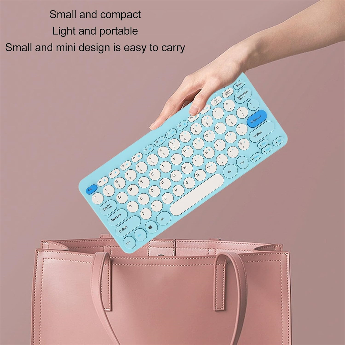 Die Hand einer Person, die eine blaue Mini-Tastatur über einer rosa Handtasche hält.