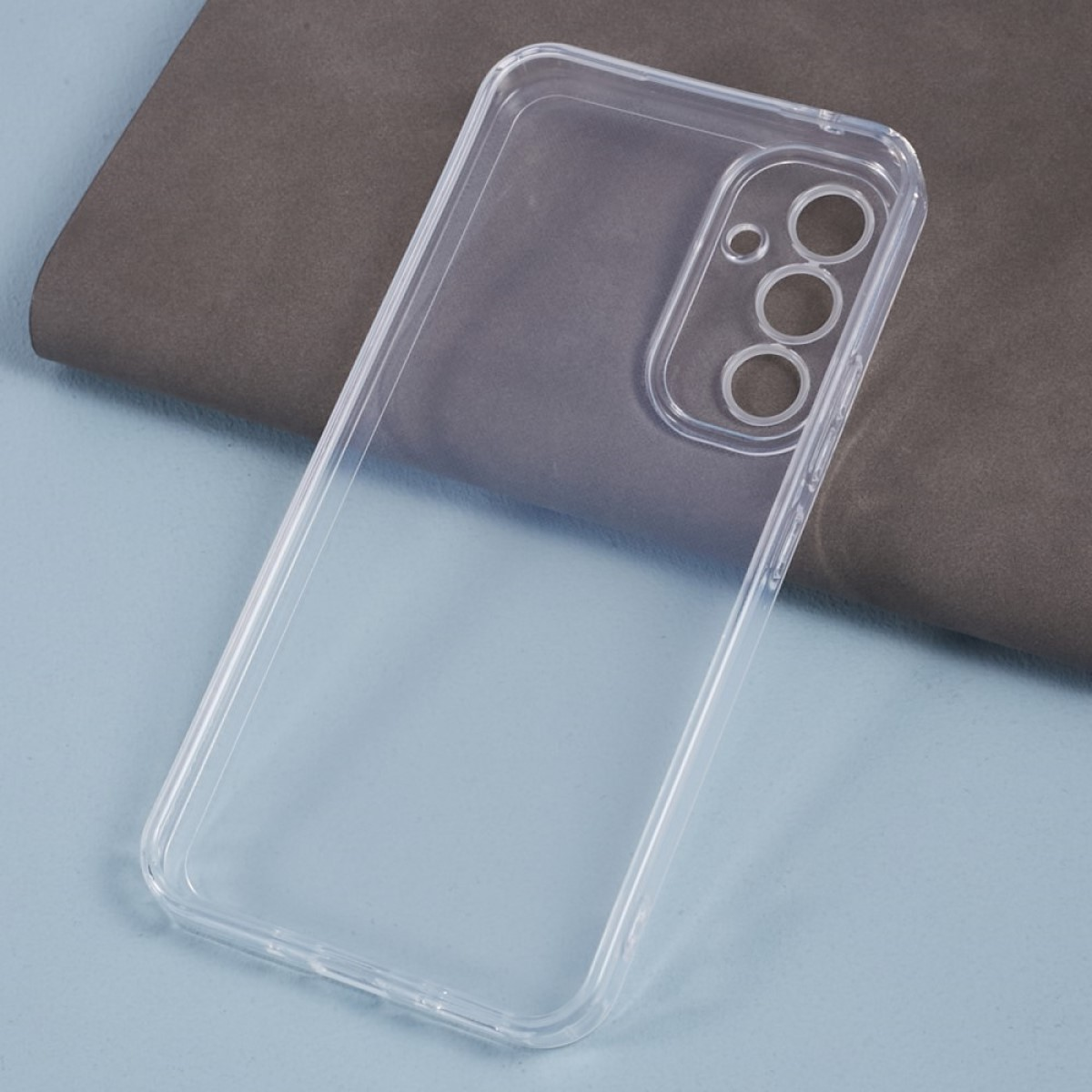 Transparente Handyhülle. Transparente Hülle mit Kameraausschnitt. Sie liegt auf einer grau-braunen strukturierten Oberfläche.