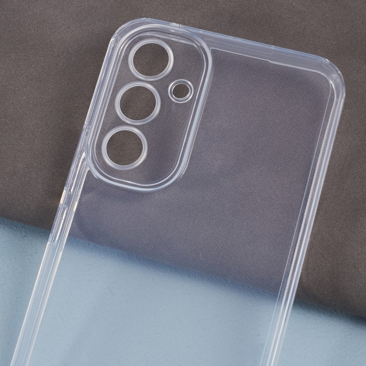 Transparente Handyhülle mit Kameraausschnitten auf strukturiertem grau-blauem Hintergrund.