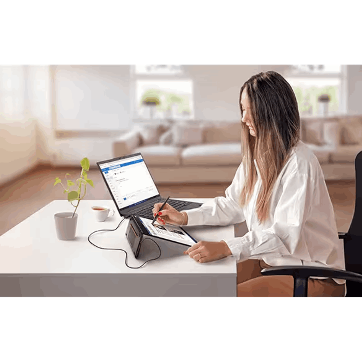 Kobieta używa laptopa i tabletu połączonych, na białym biurku w salonie.