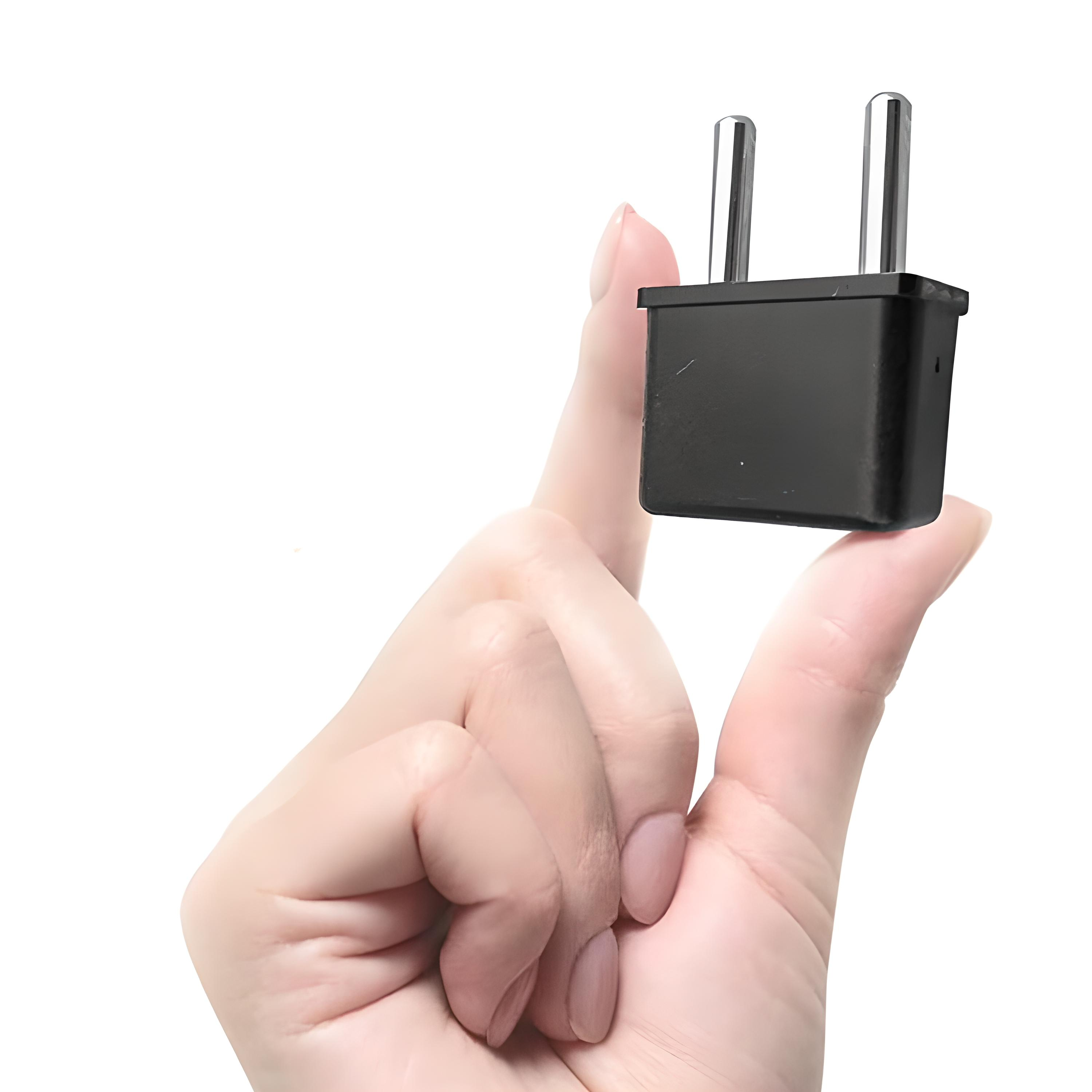 Ein schwarzer elektrischer Stecker, der von einer Hand gehalten wird. Der Stecker hat zwei Stifte und einen quadratischen Körper.