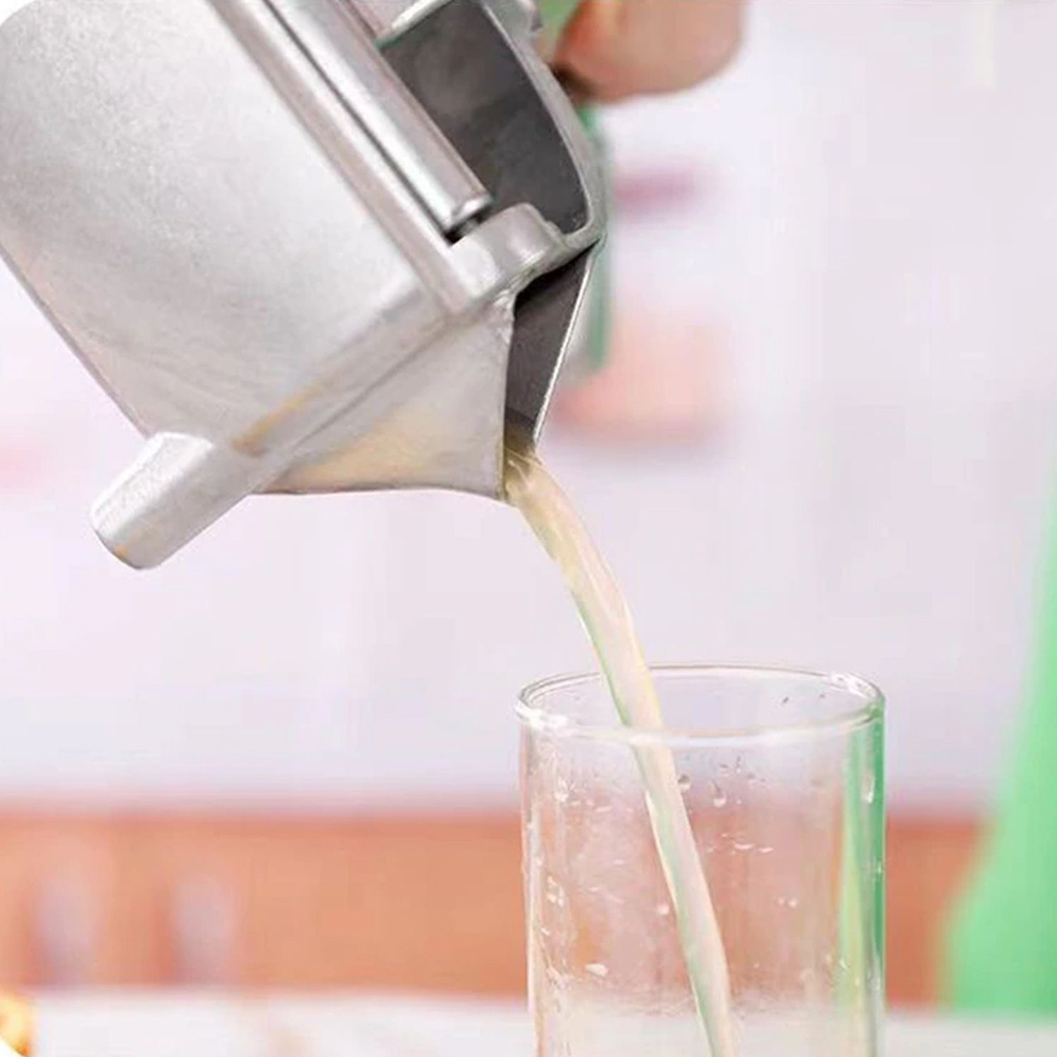 Ein Metallentsafter, der Saft in ein klares Glas gießt, mit verschwommenem Hintergrund.