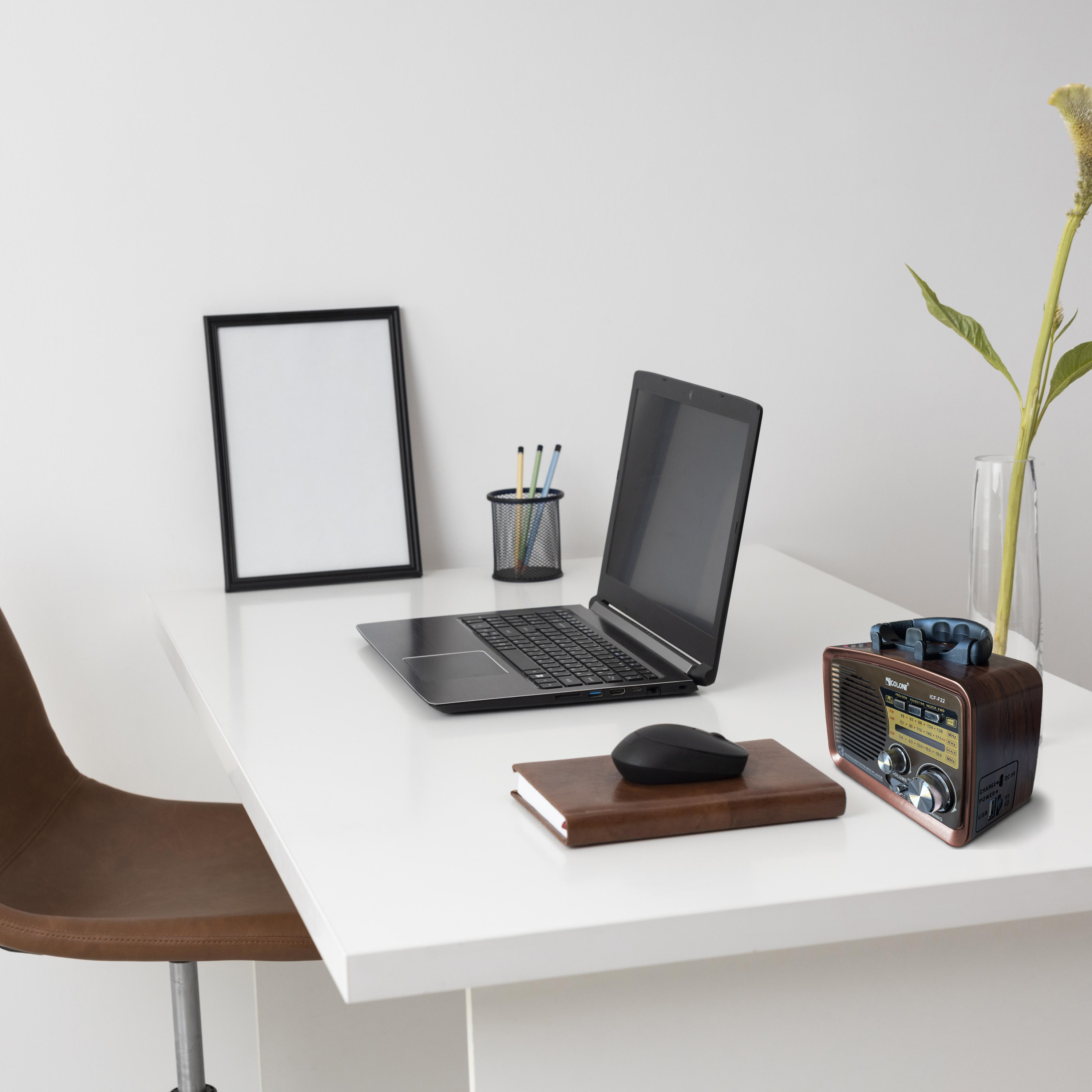 Weißer Schreibtisch mit Laptop, Radio, Notizbuch, Stiften und Bilderrahmen.