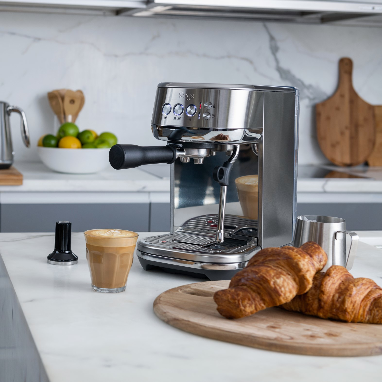 Eine Espressomaschine mit einer Tasse Latte und Croissants auf einer Marmorarbeitsplatte.