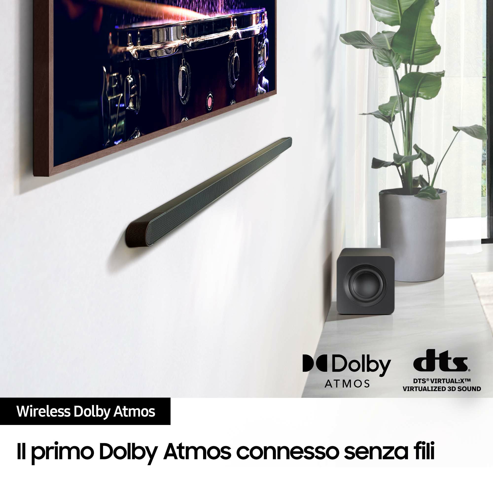 Black soundbar below a TV. Black subwoofer on the right. White wall.  Dolby Atmos and DTS logos are visible.