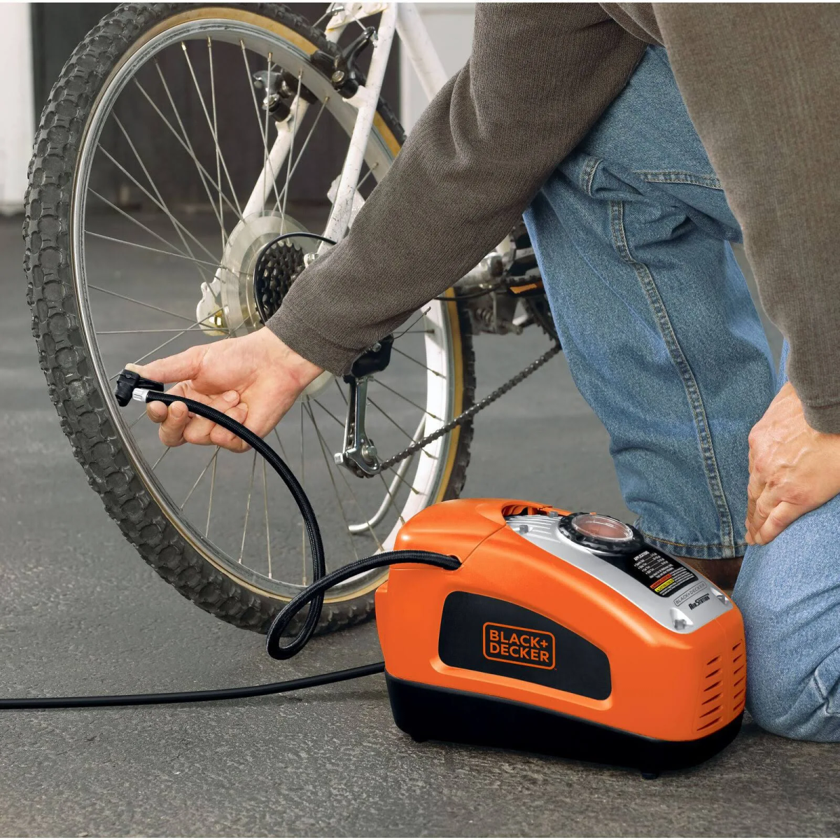 Mann, der einen Fahrradreifen mit einem orangefarbenen und schwarzen Luftkompressor aufpumpt.