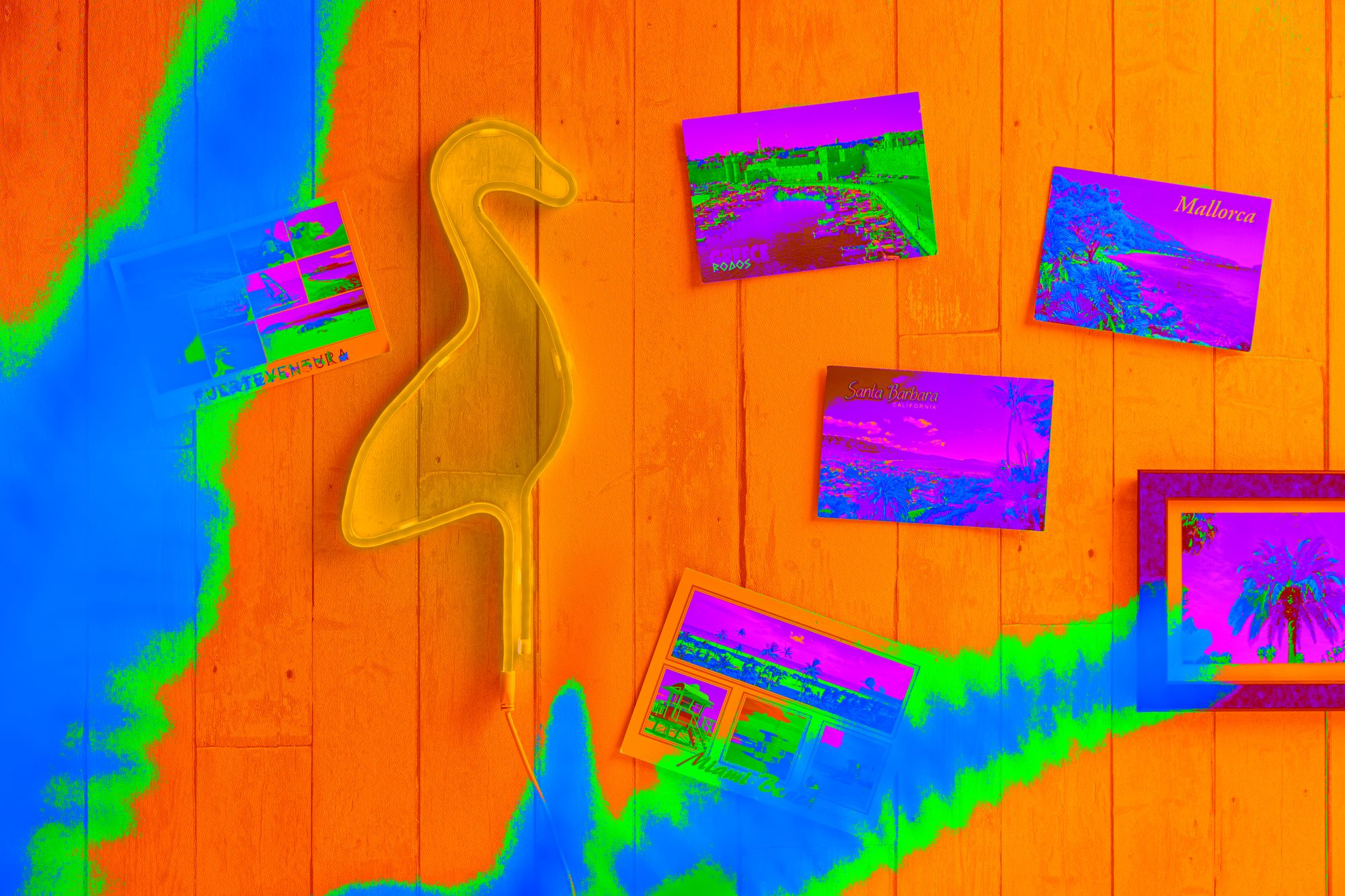 Pomarańczowa drewniana powierzchnia z neonowym światłem flaminga i pocztówkami z kolorowymi obrazami.