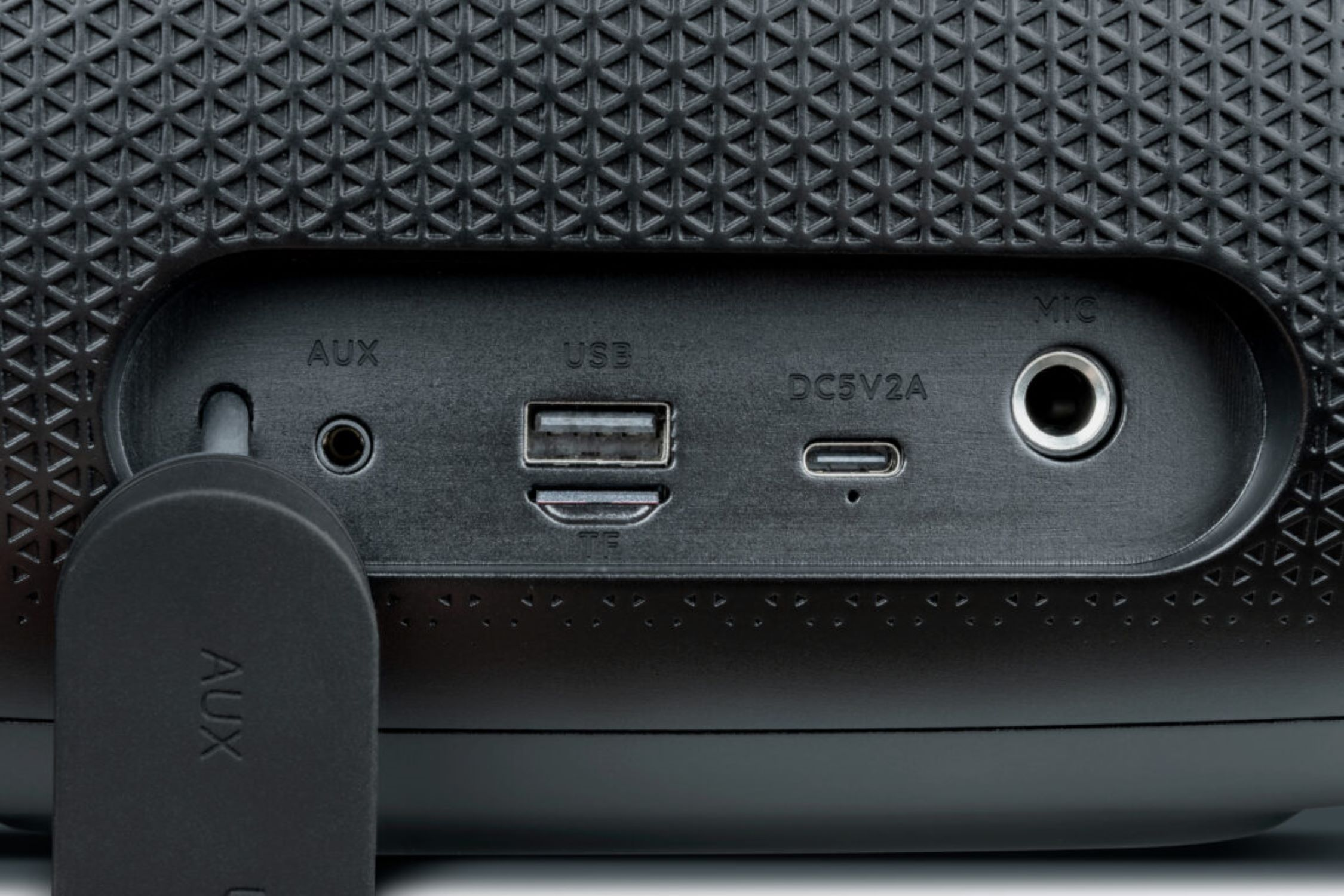Primo piano delle porte dell'altoparlante: AUX, USB, DC5V2A e MIC. Un cavo AUX è collegato.